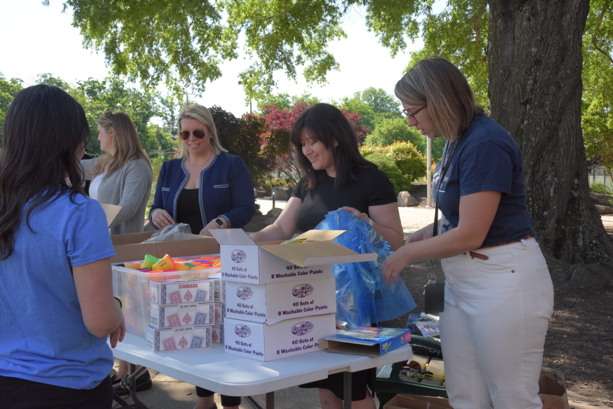 a group of women full plastic bags with arts and craft supplies