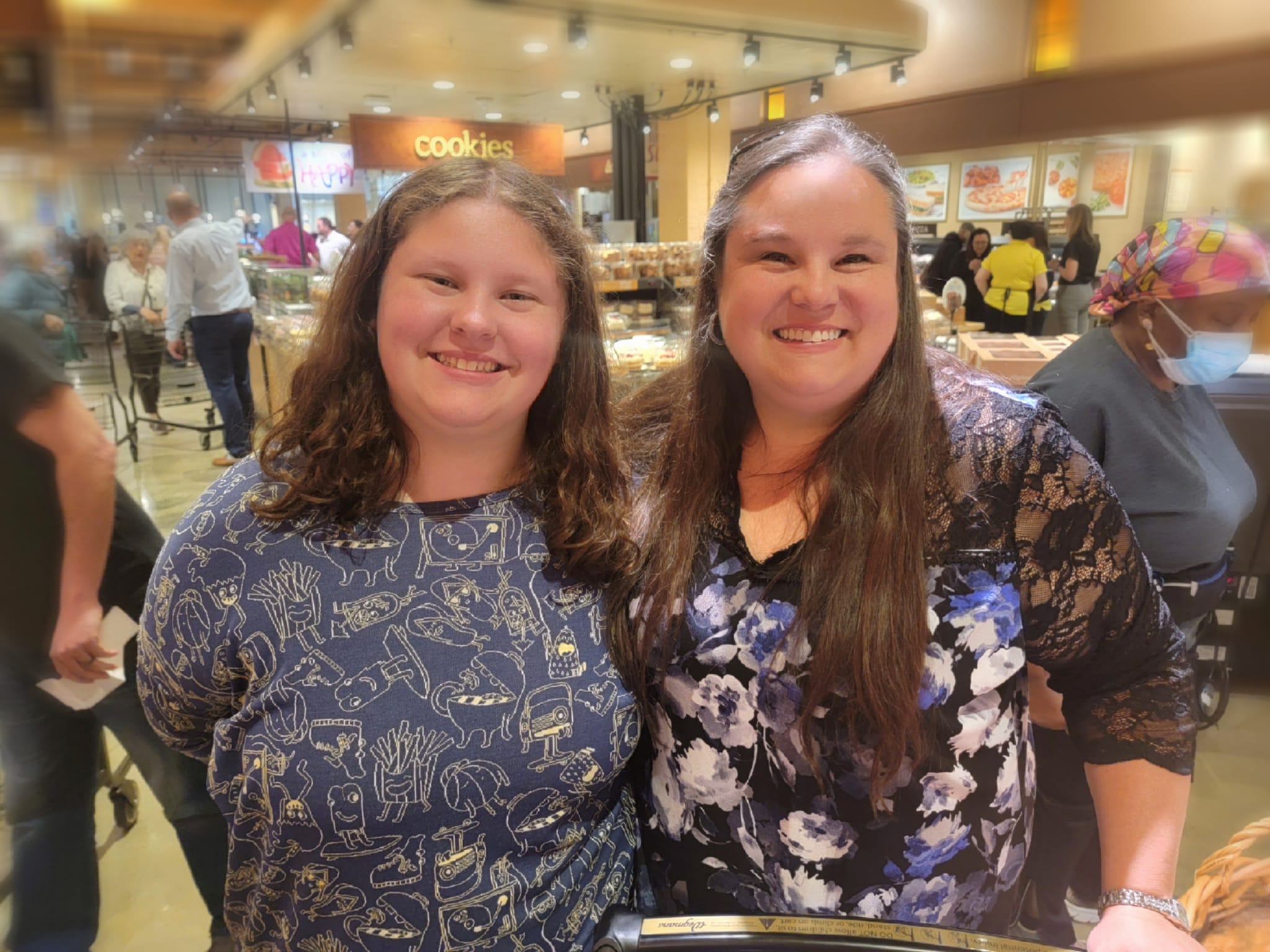 a mother and her daughter smile together inside a Wegmans grocery store