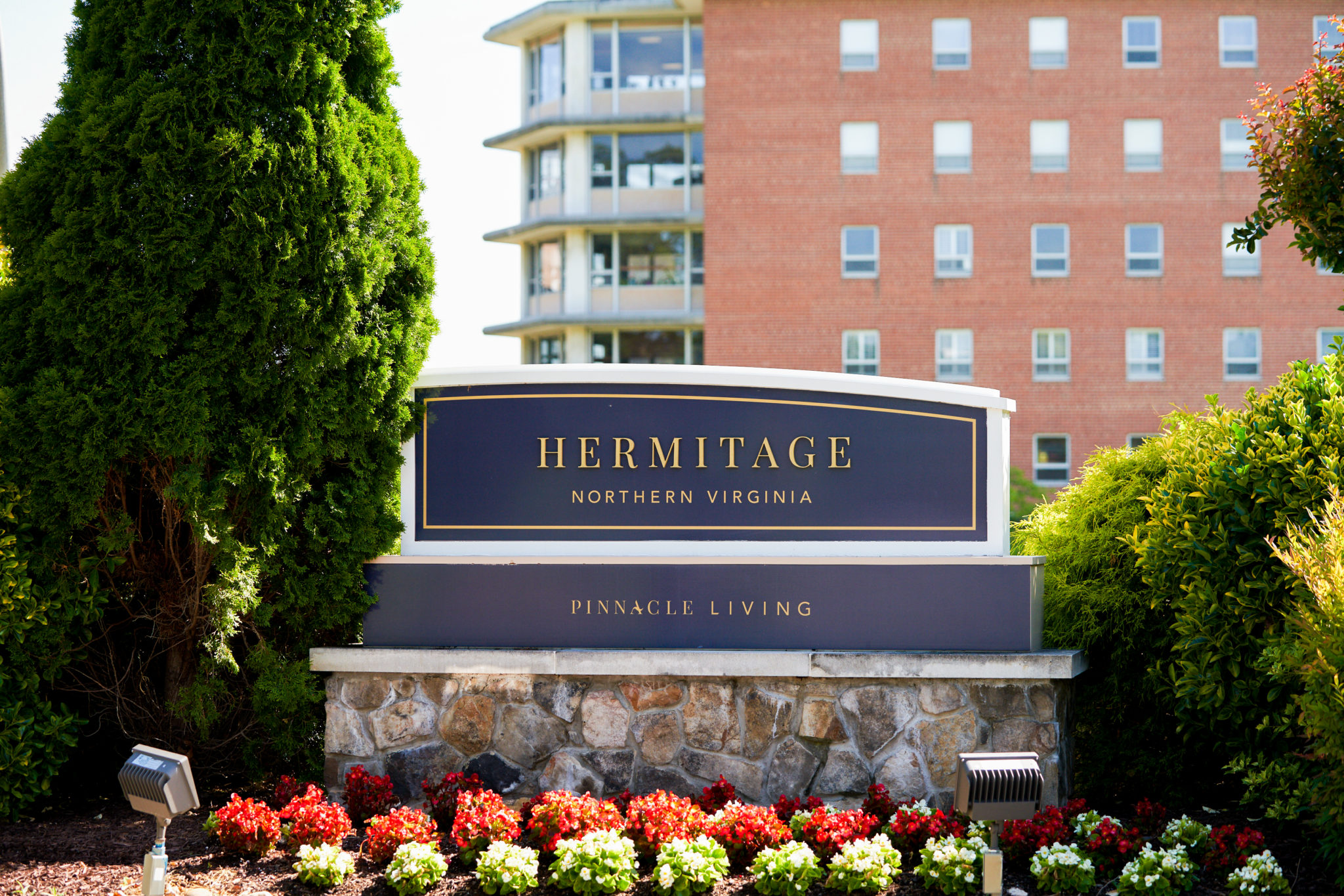 a sign outdoors in front of a high rise building that reads Hermitage Northern Virginia Pinnacle Living 