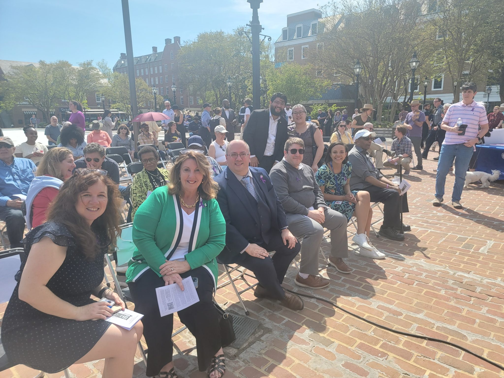 group of people sit outside in chairs and smile at camera