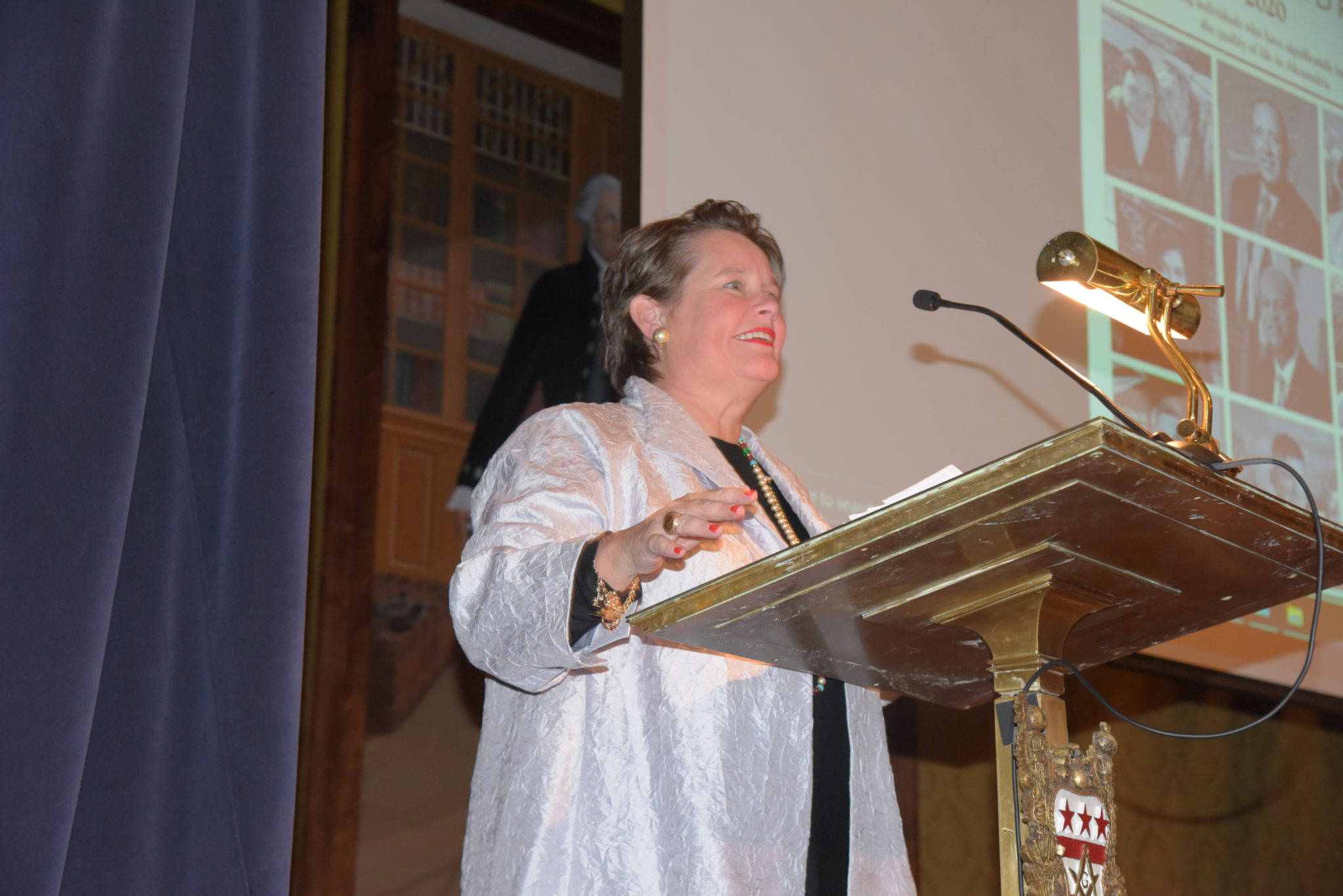 woman stands at podium with hands in air 