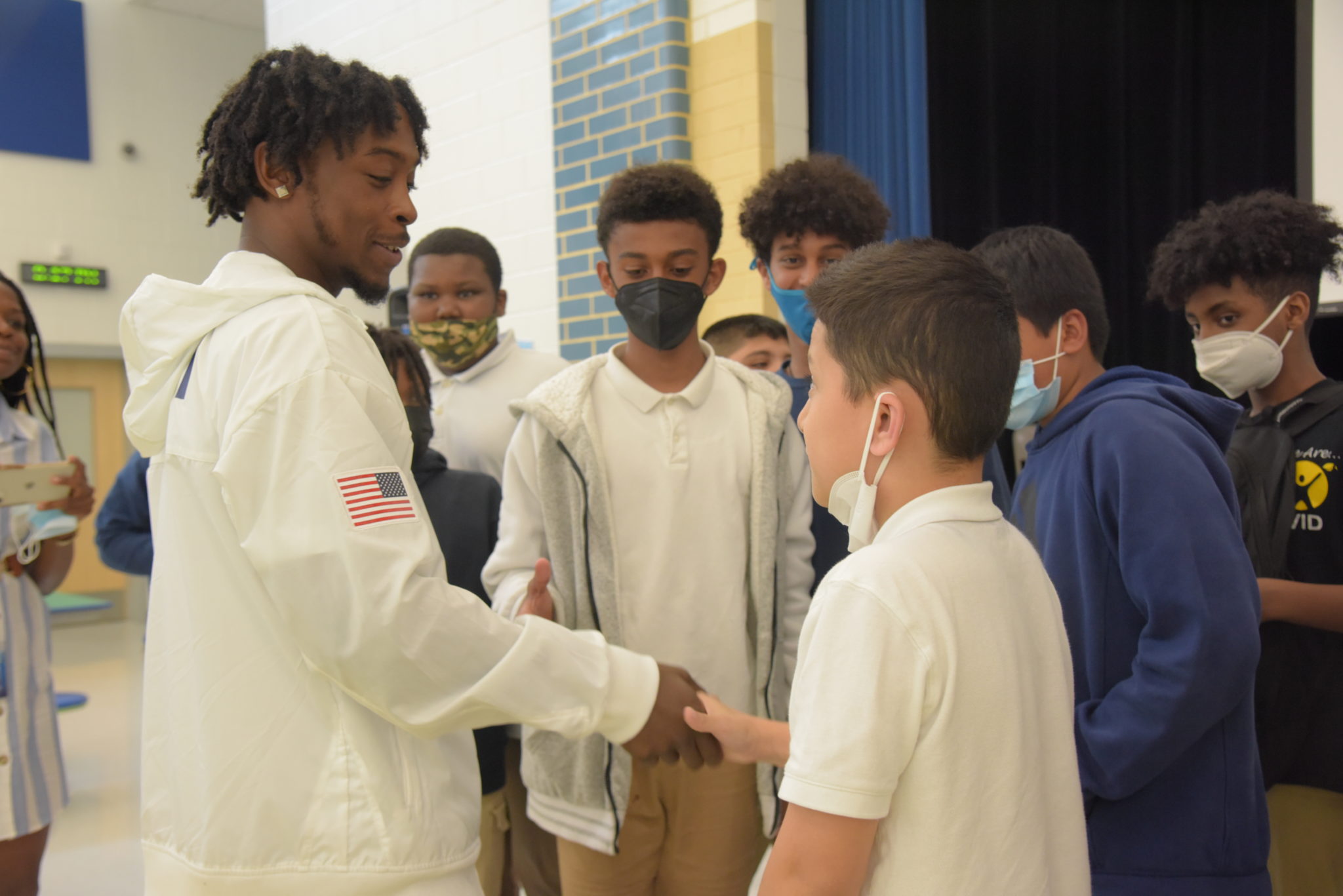 middle school age boys shake hands with olympic male boxer