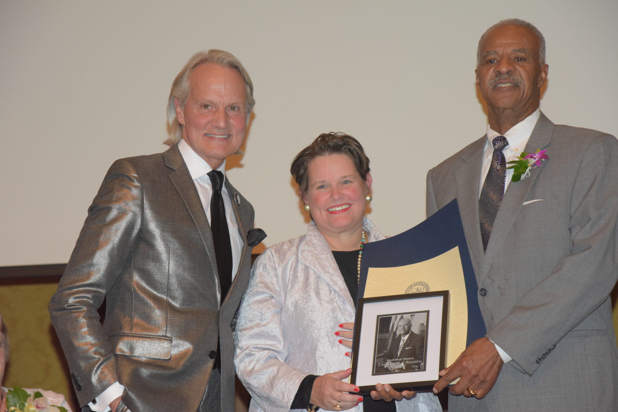 McAthur Myers holds photo and certificates and stands next to Mary Wadland and Monte Durham