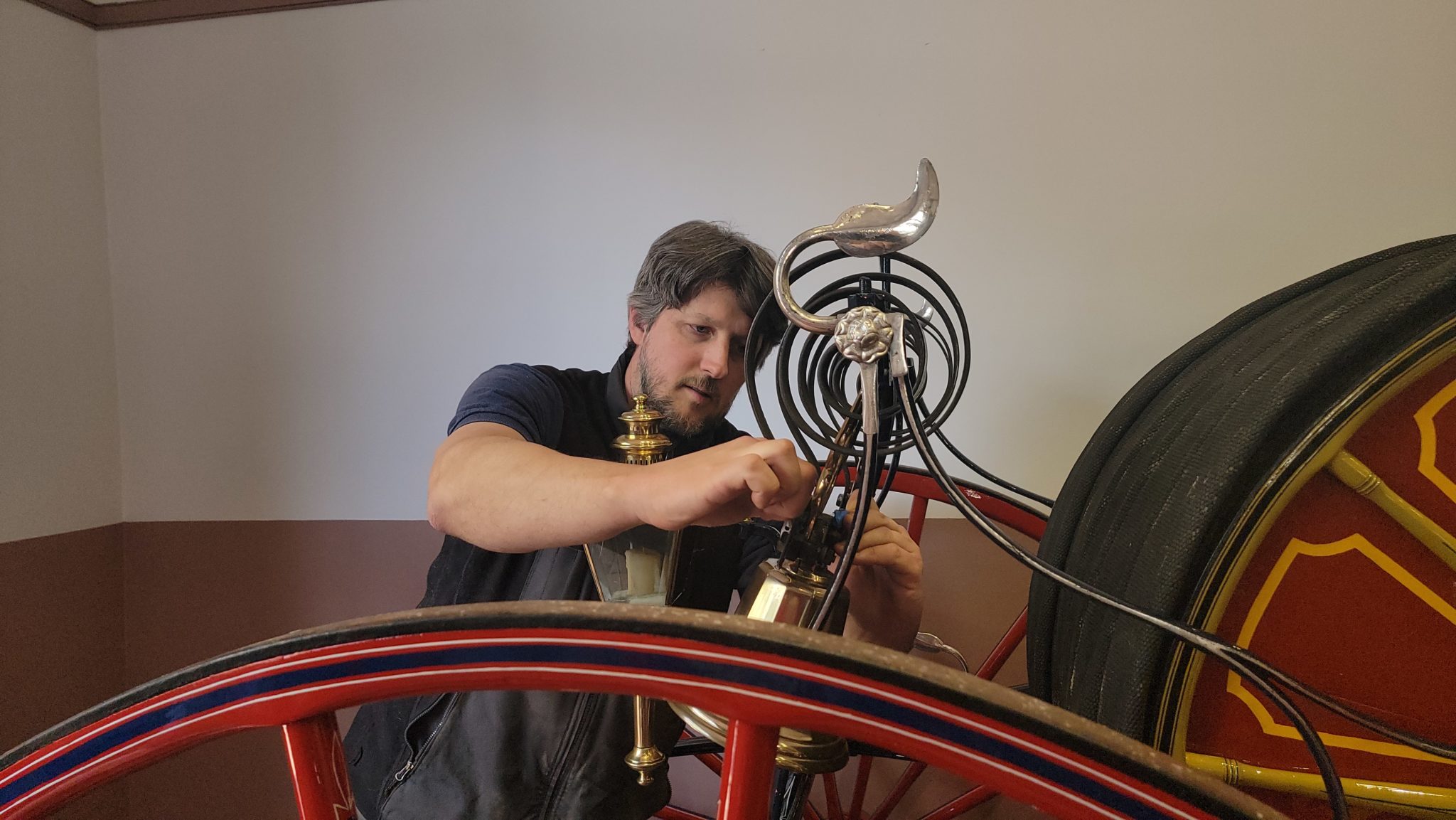 man attaches bell to hose-reel carriage