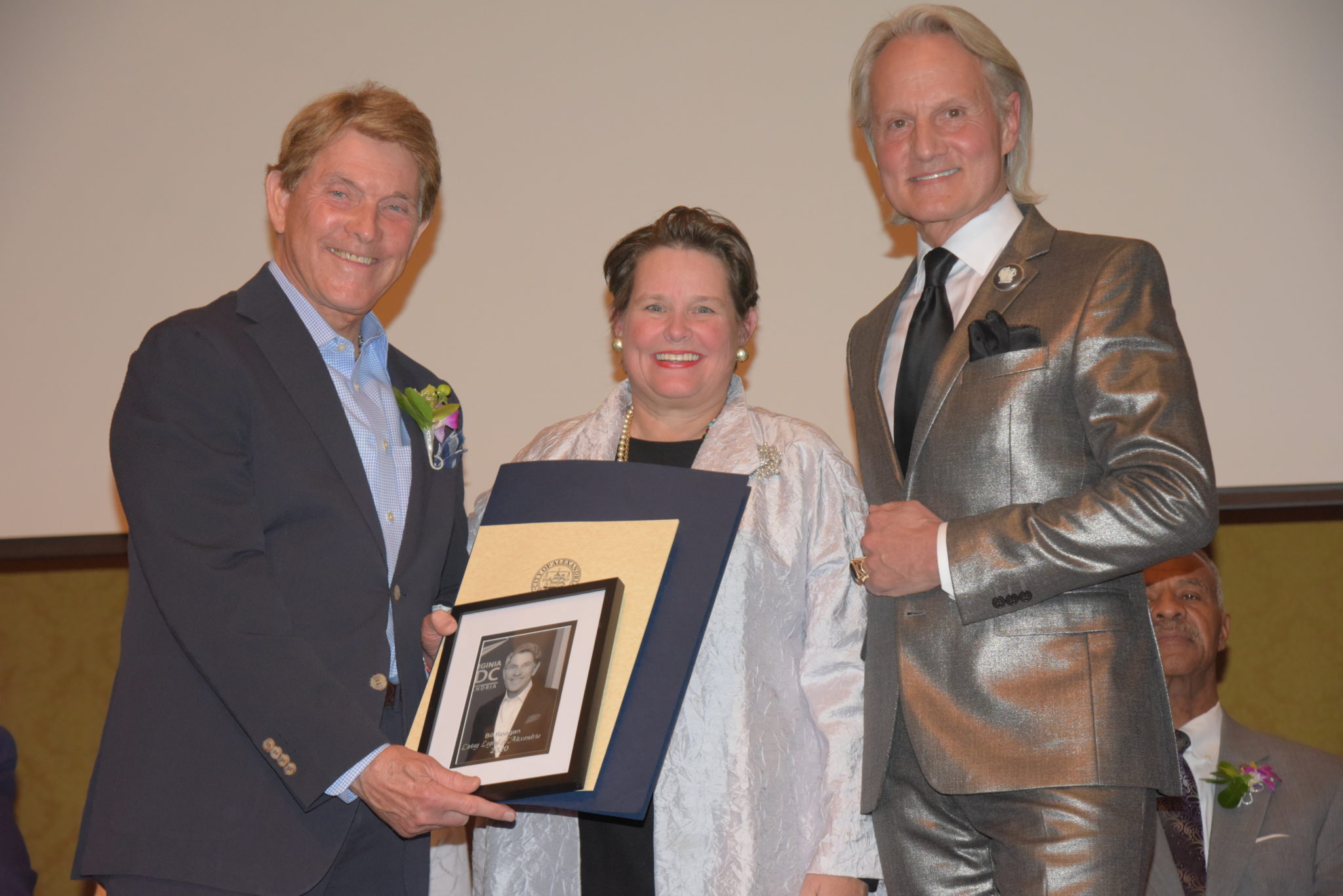 Dill Reagan holds photo and certificates and stands next to Mary Wadland and Monte Durham