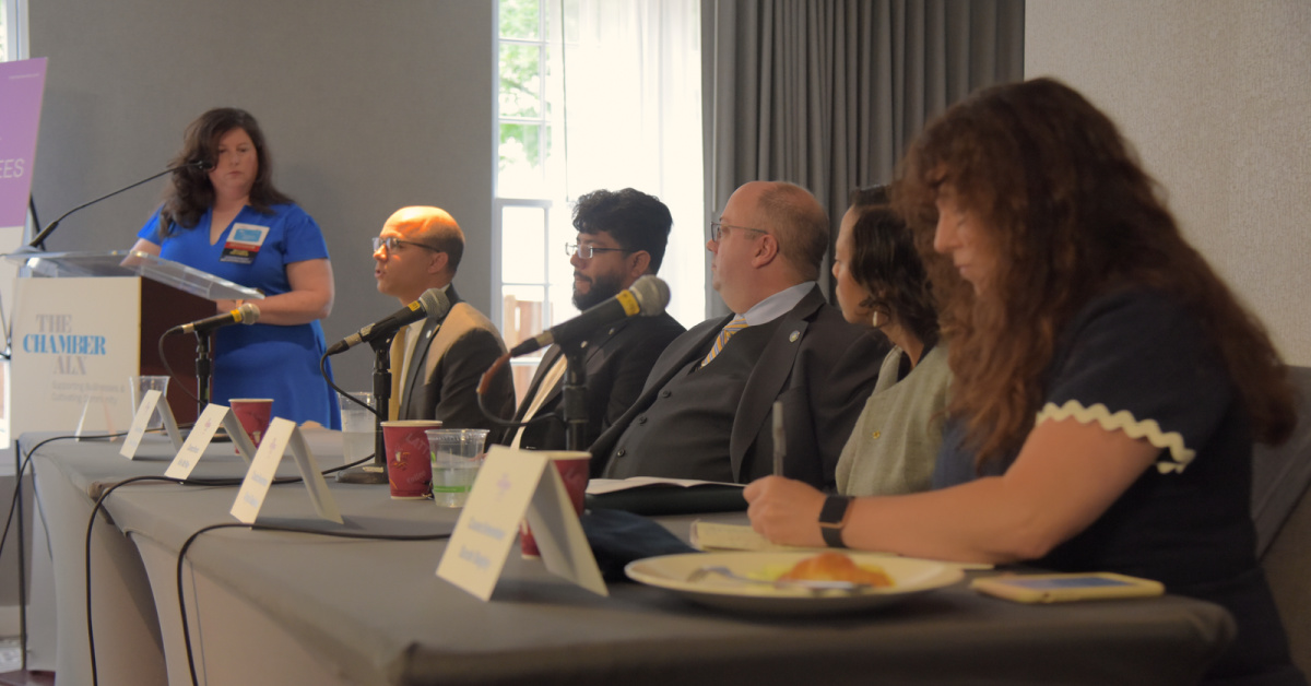 panel of city council members sit behind microphones 