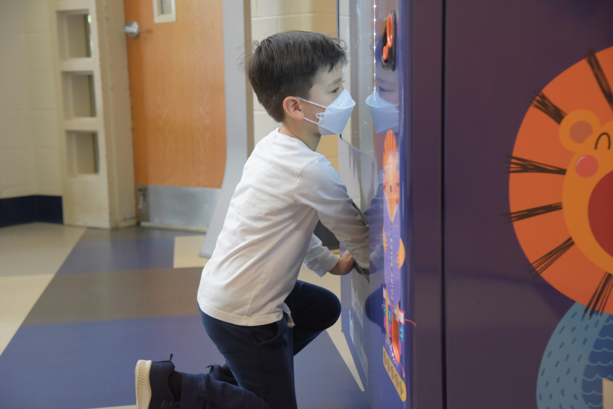 a young boy reaches his hands inside the slot of a vending machine