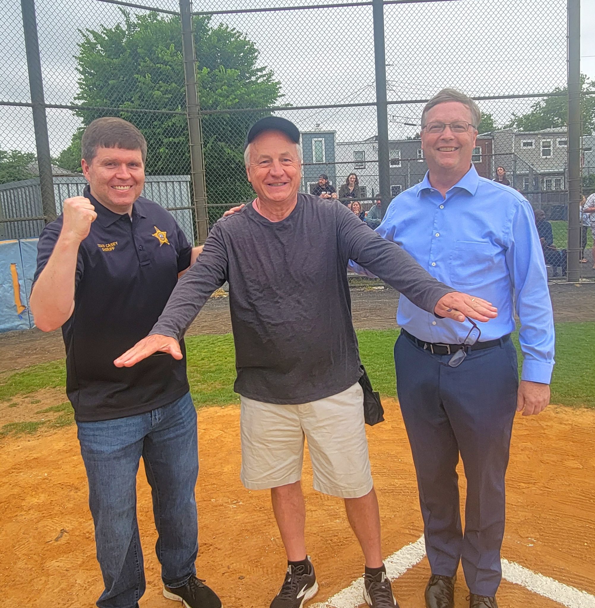 alexandria sheriff sean casey and former sheriff dana lawhorne and alexandria city manager james paragon stand on a baseball field