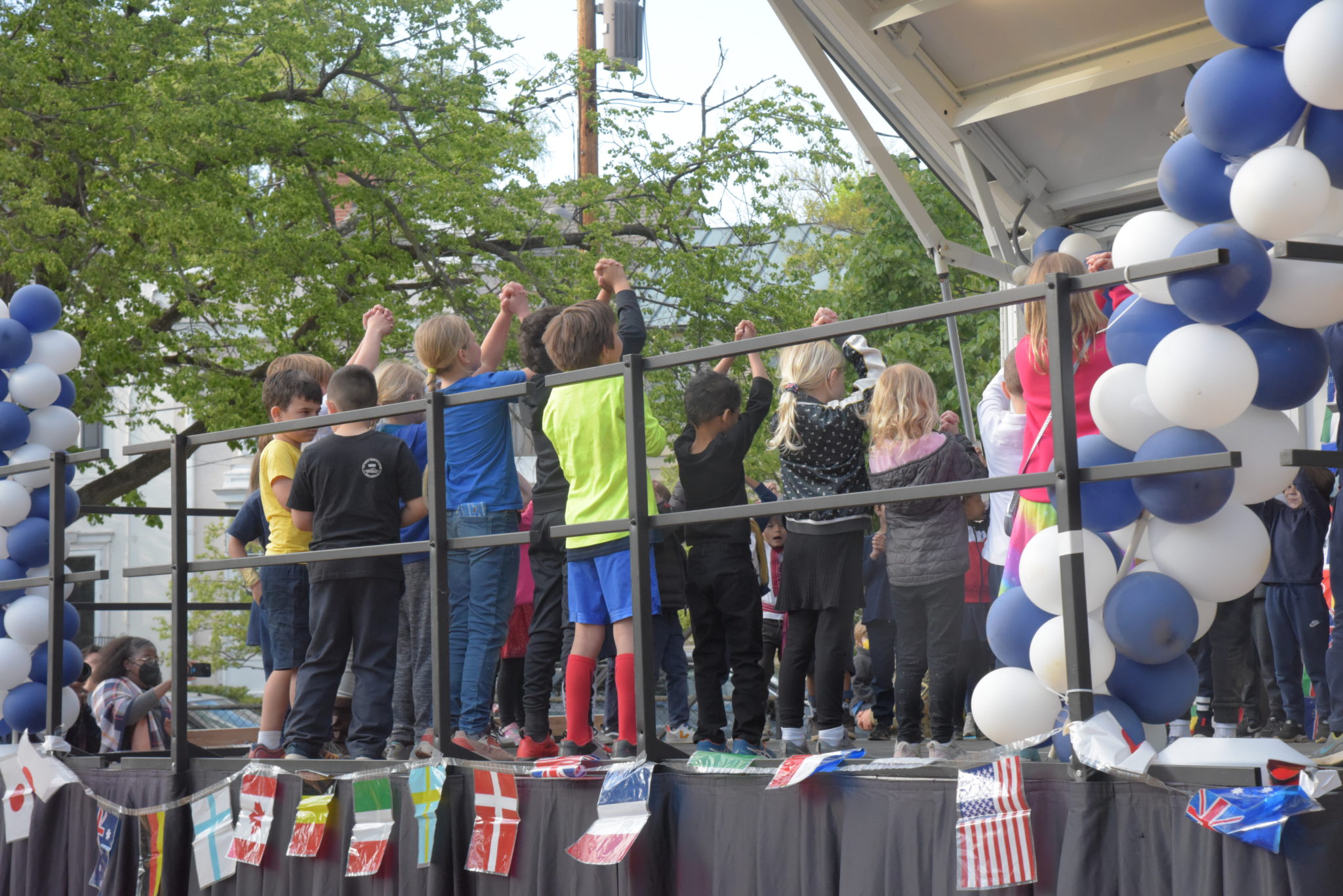 students on stage raising hands in a circle