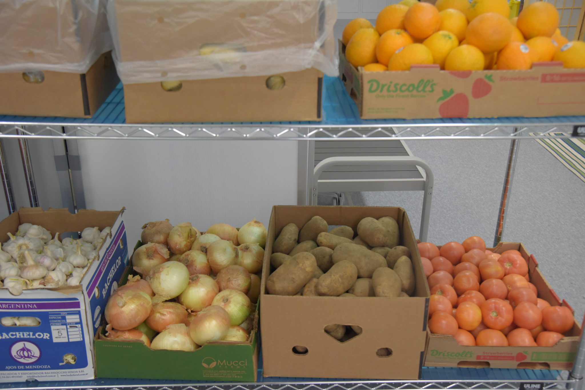 boxes of potatoes, onions, and oranges