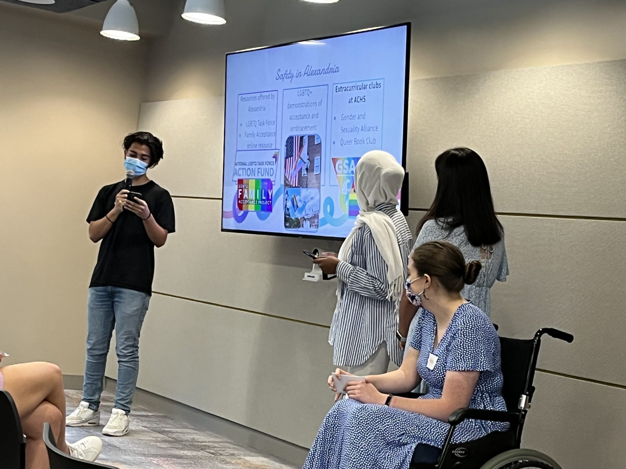 a boy and three girls, one in a wheel chair, stand in front of a smart board to present a project to Alexandria City Council 