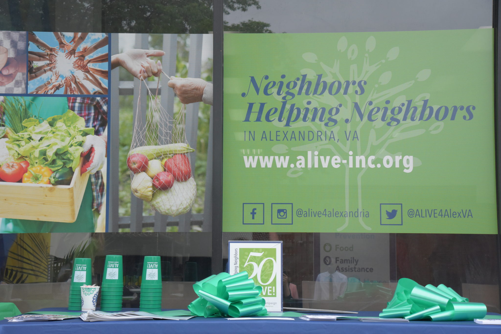 a banner in a window which reads Neighbors Helping Neighbors, www.alive-inc.org