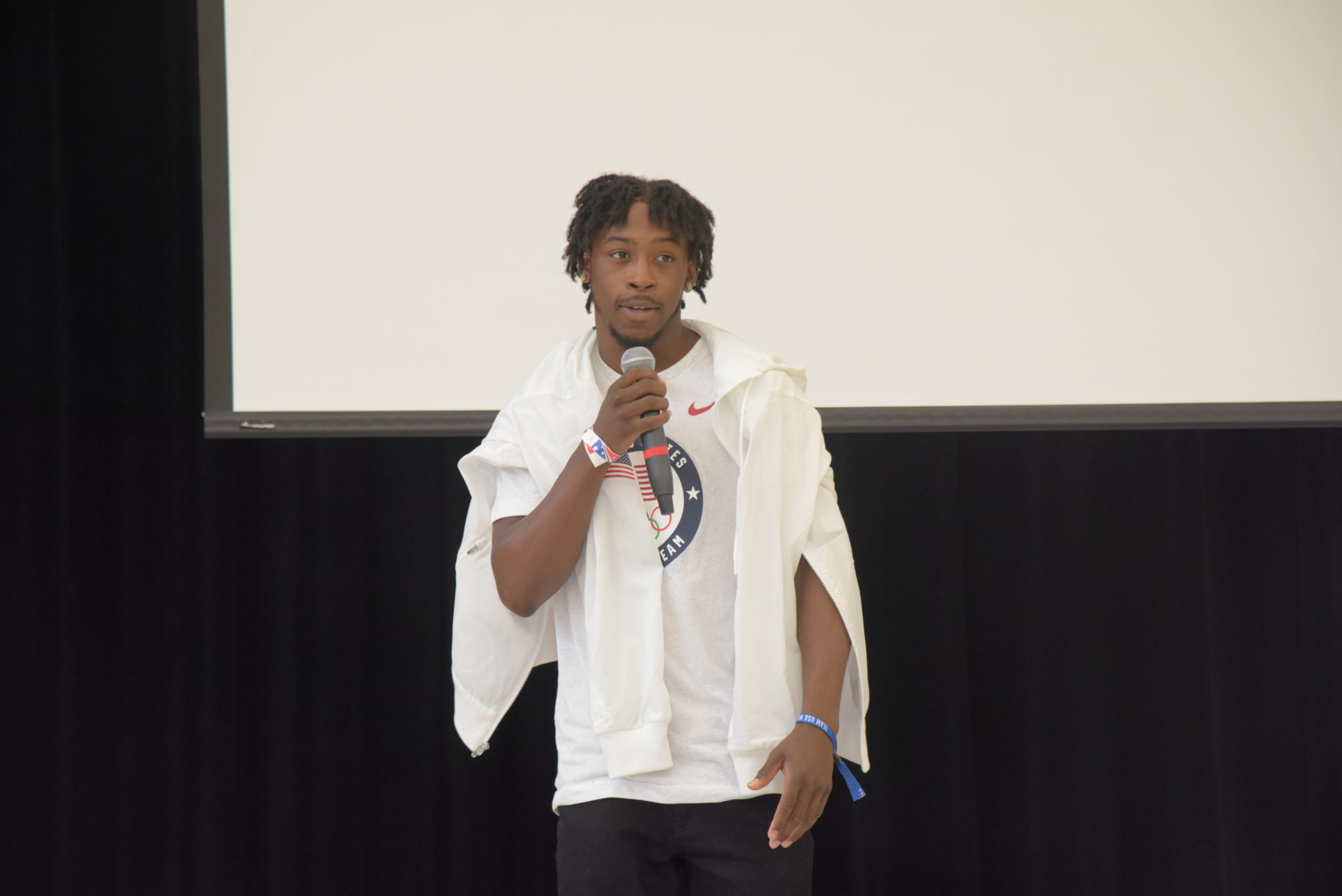 man speaks on stage holding microphone