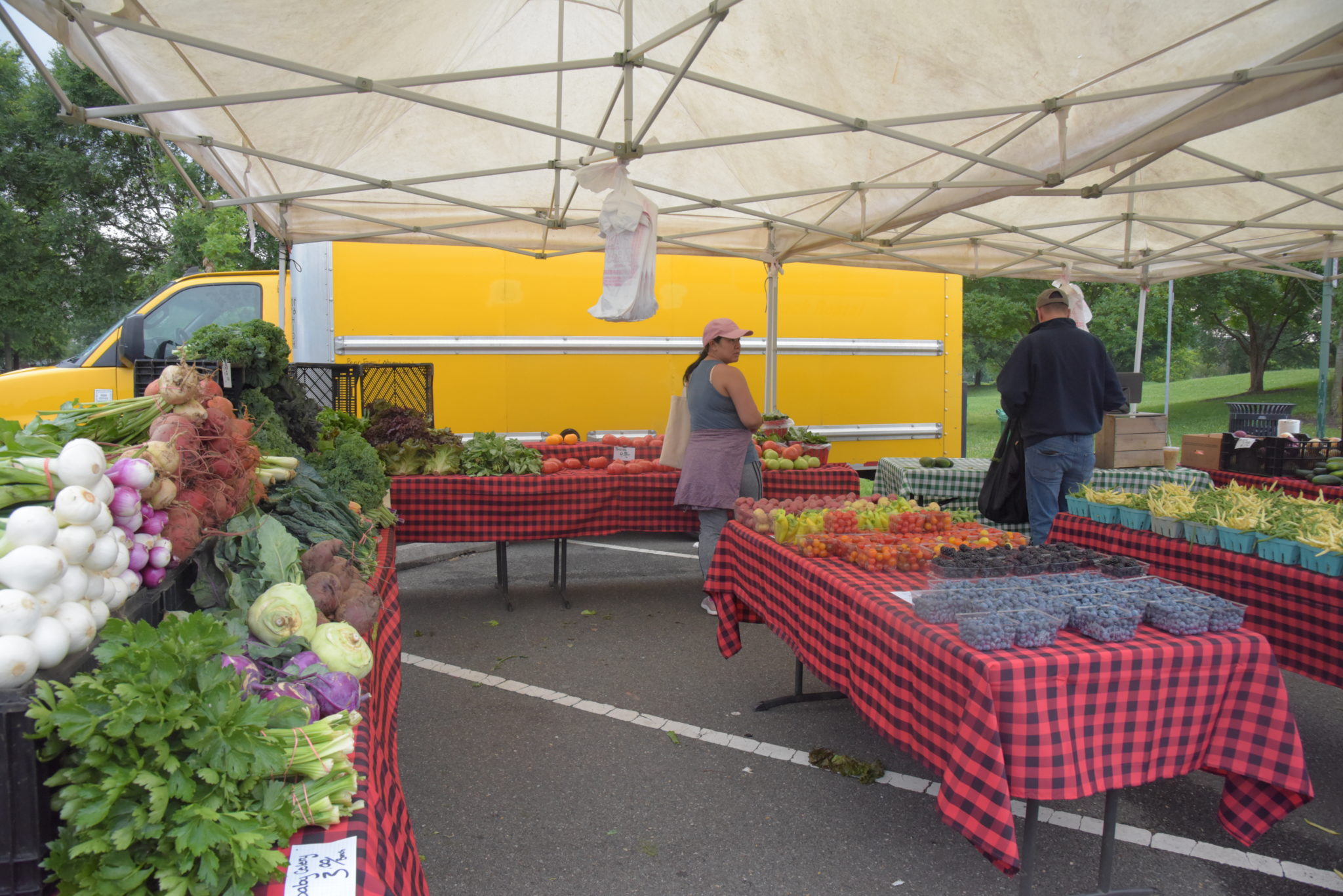 a trio of tables with red tables cloths and vegetables sitting on top of each