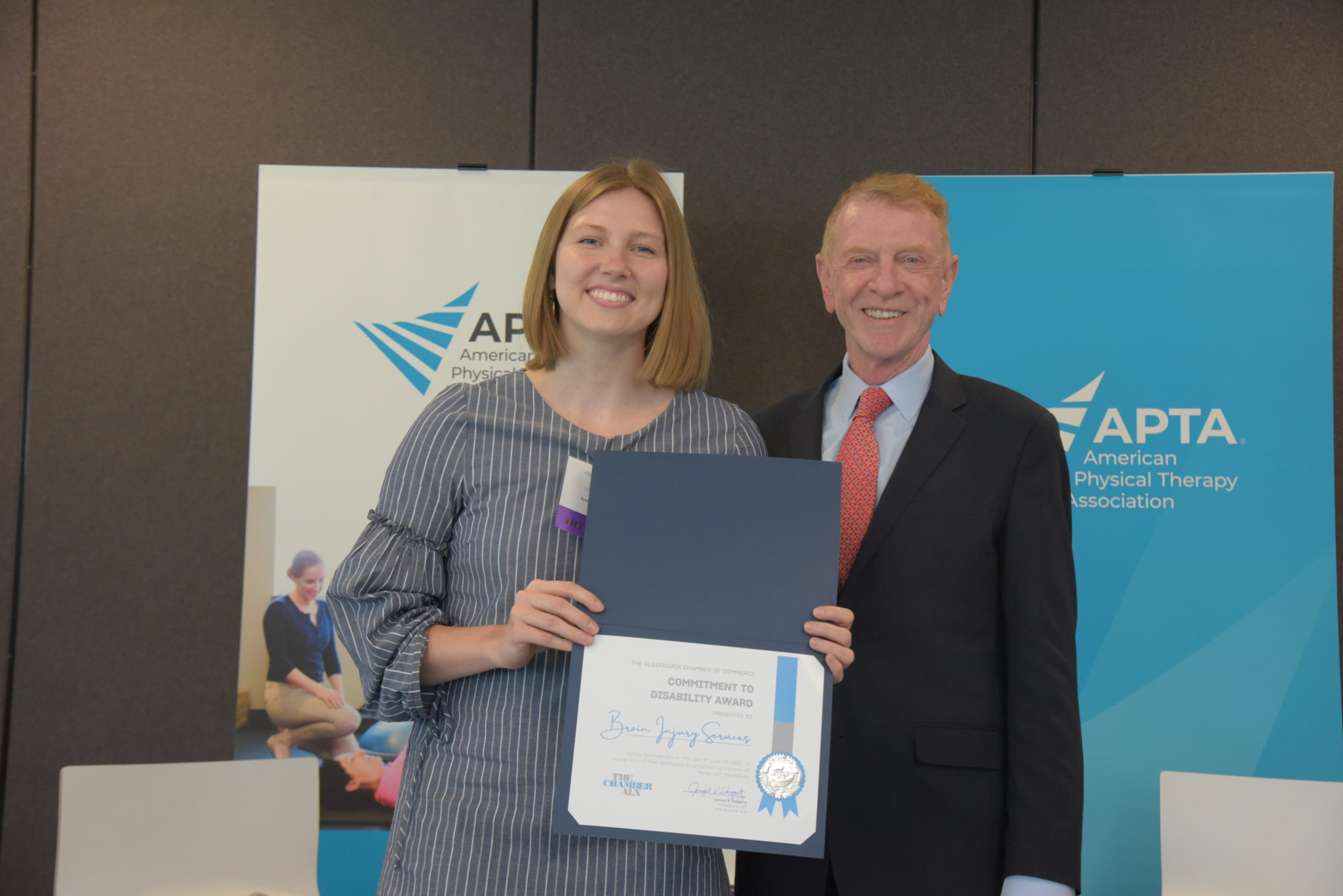 a woman holding a certificate stands next to chamber president Joe Haggerty