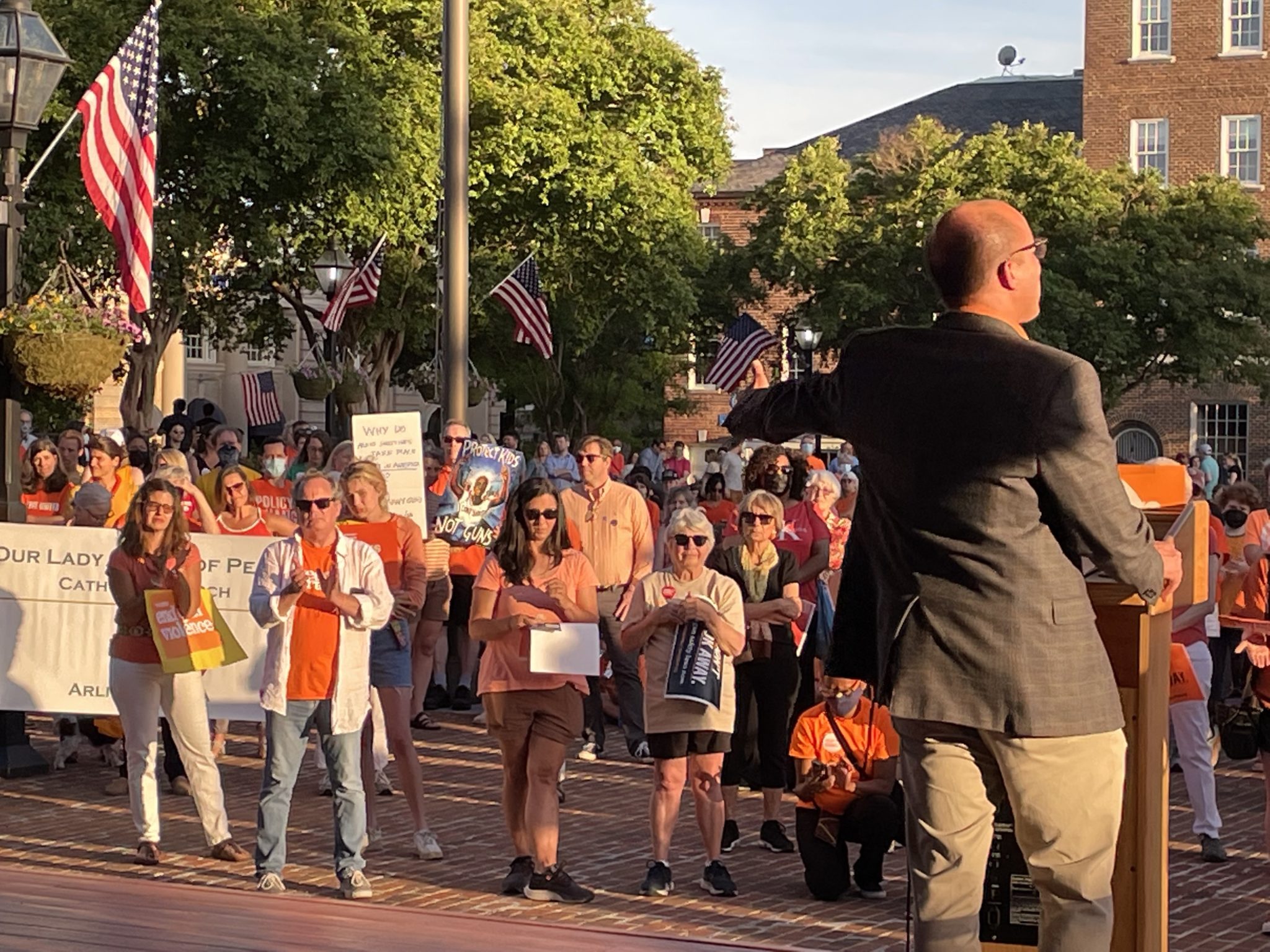 Alexandria Mayor Justin Wilson faces a crowd of people in orange t shirts