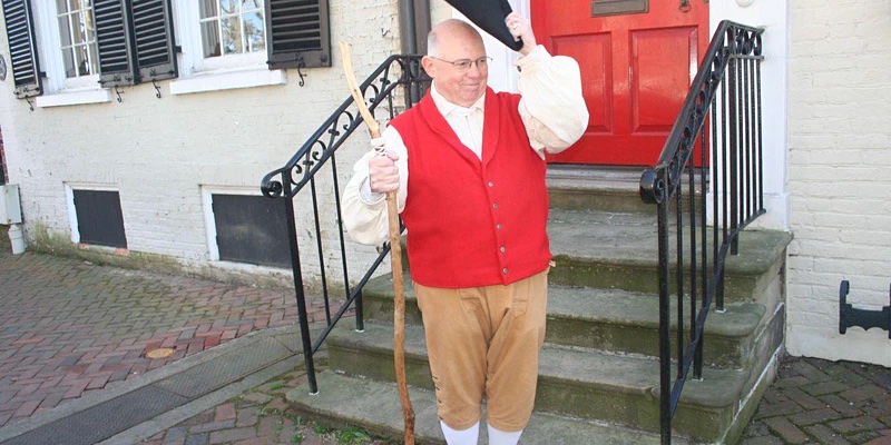 a tour of George Washington's historic Alexandria a man stands in front of steps in Old Town with 1800s attire