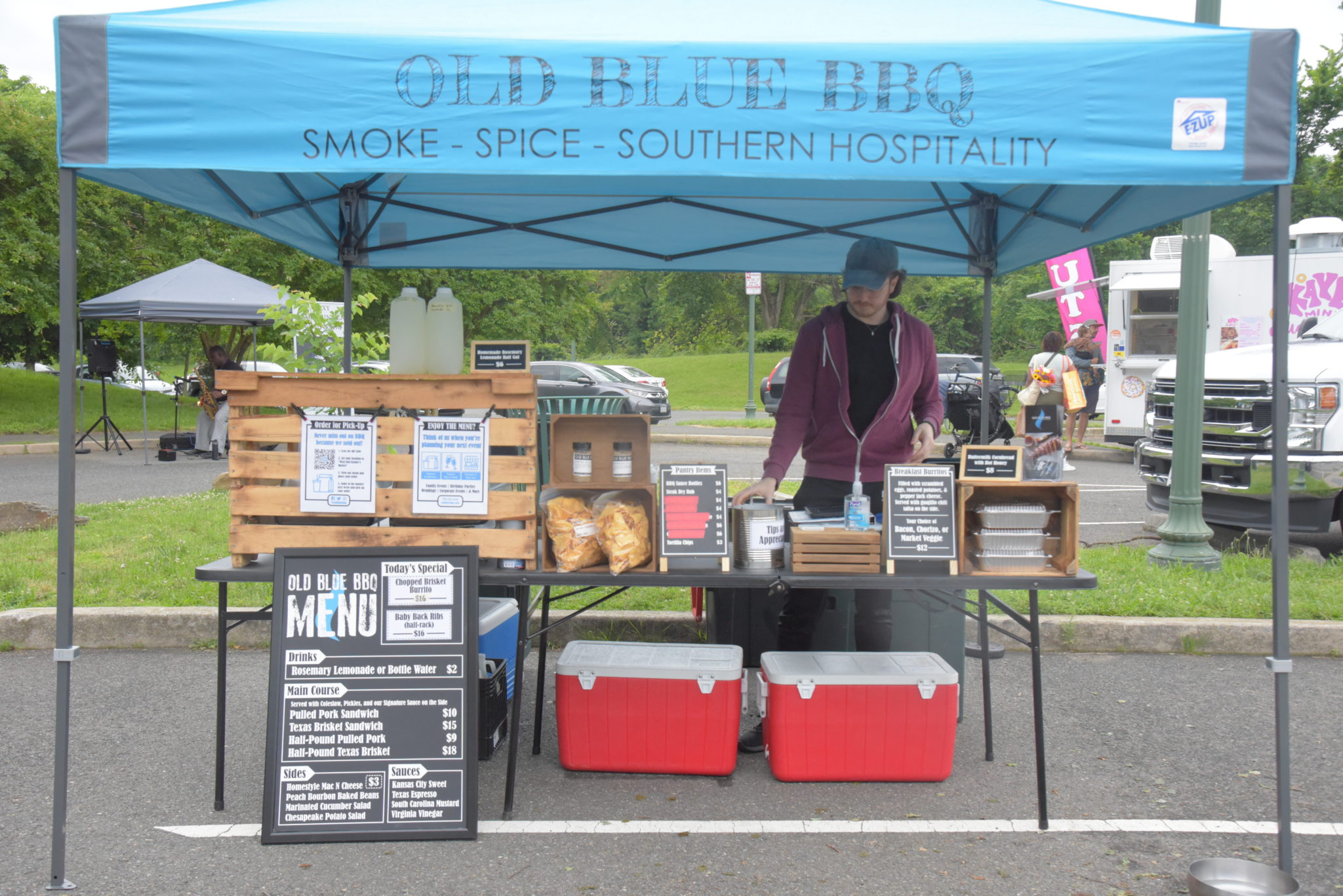 a blue tent covering a barbecue stand at the west end farmers market