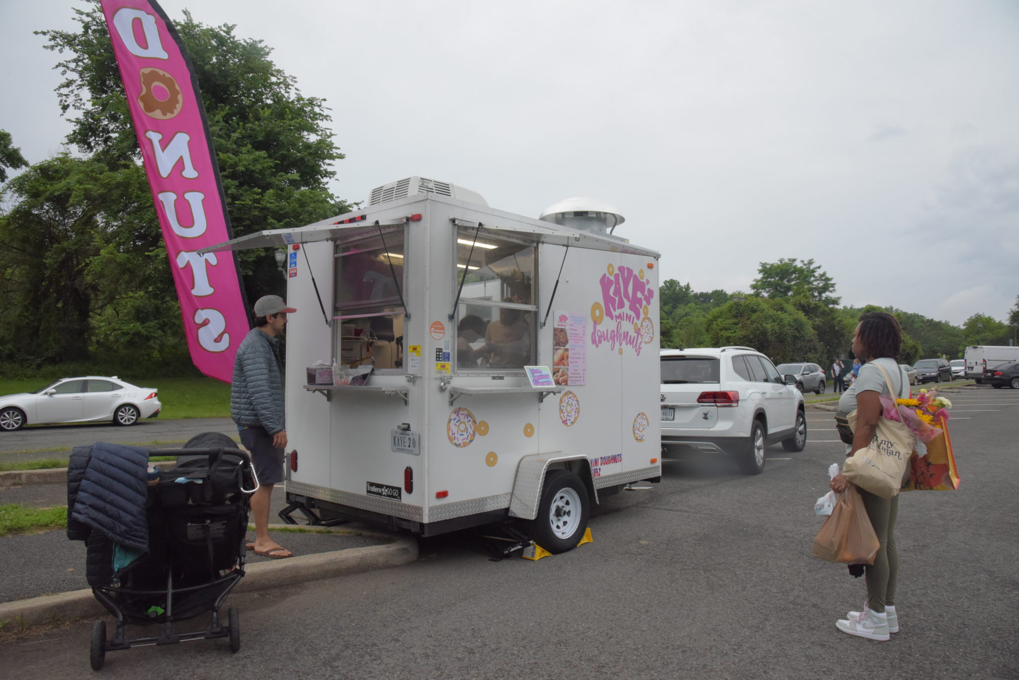 a food truck serving mini donuts with a pink flag that reads "Donuts"