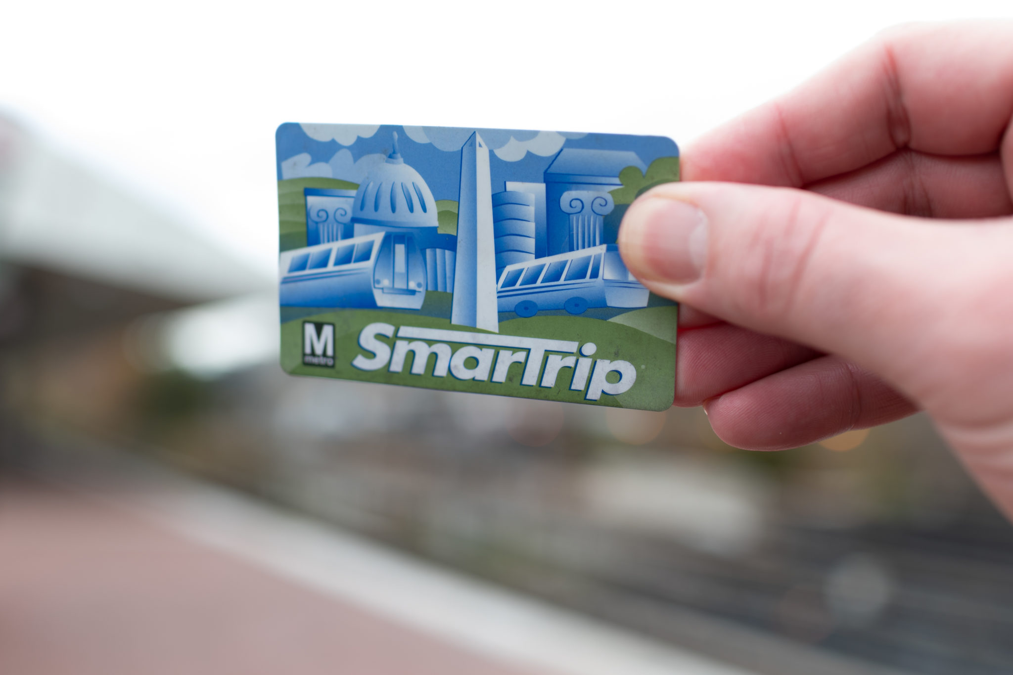 image shows a hand holding a SmarTrip metro card for the Washington DC, Metropolitan area