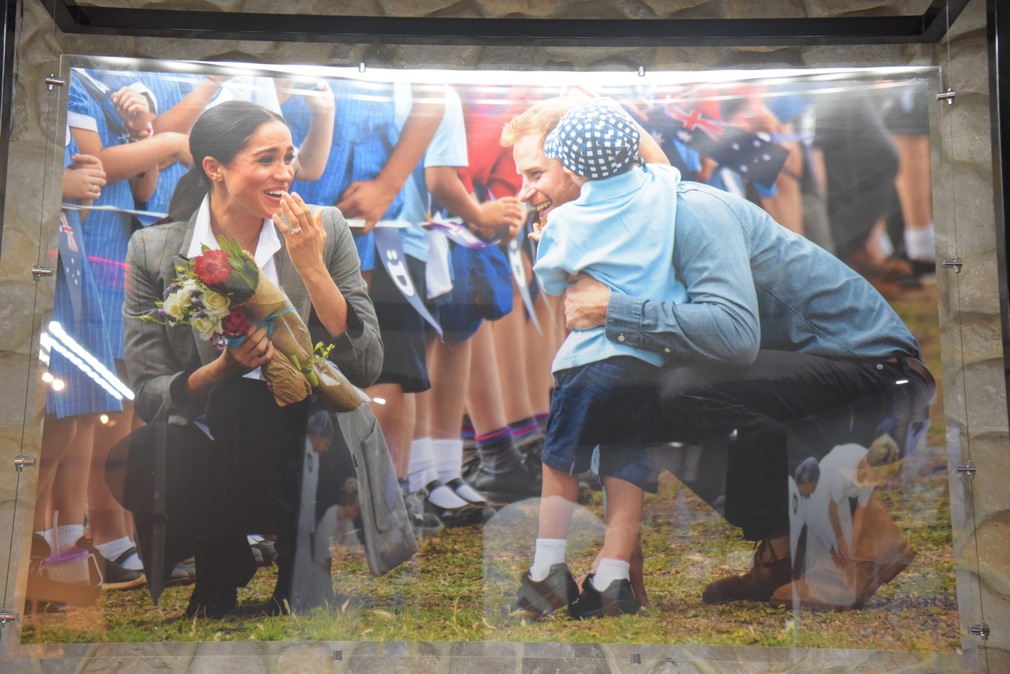 Megan Markle and Prince Harry visit children in Australia, one boy in a hat grabs Harry's red hair