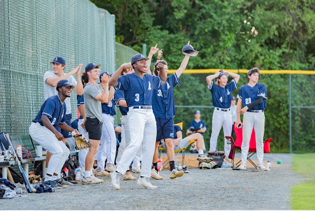 a group of baseball players for the Alexandria Aces cheer in the dugout