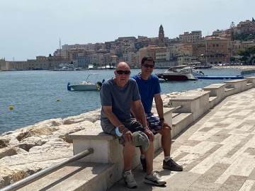 two men sit on the coast of the sea in Italy