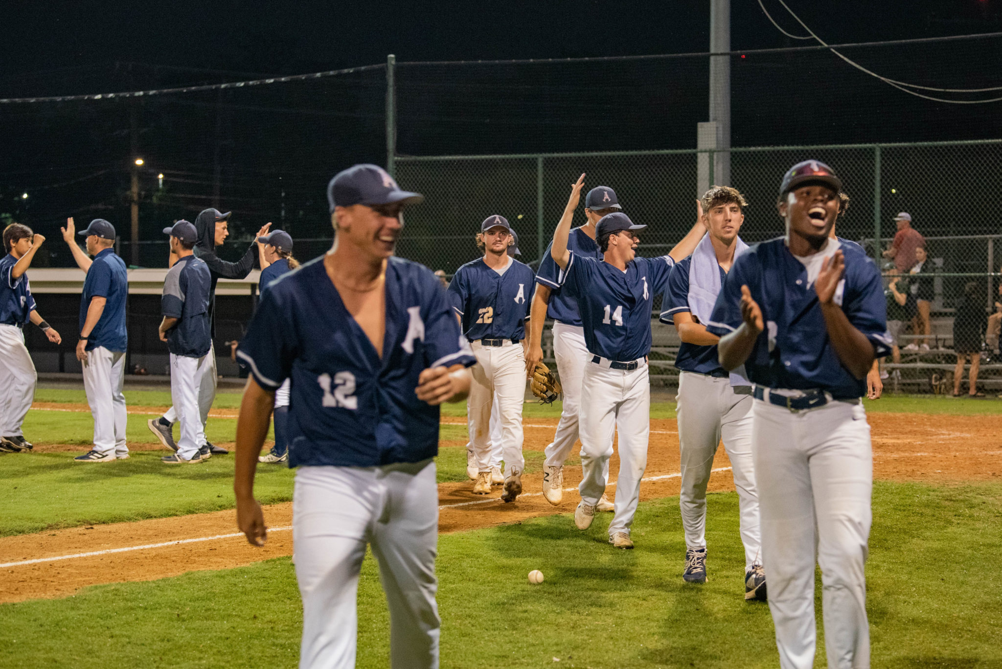 Members of the Alexandria Aces walk off the field with arms in air celebrating a victory