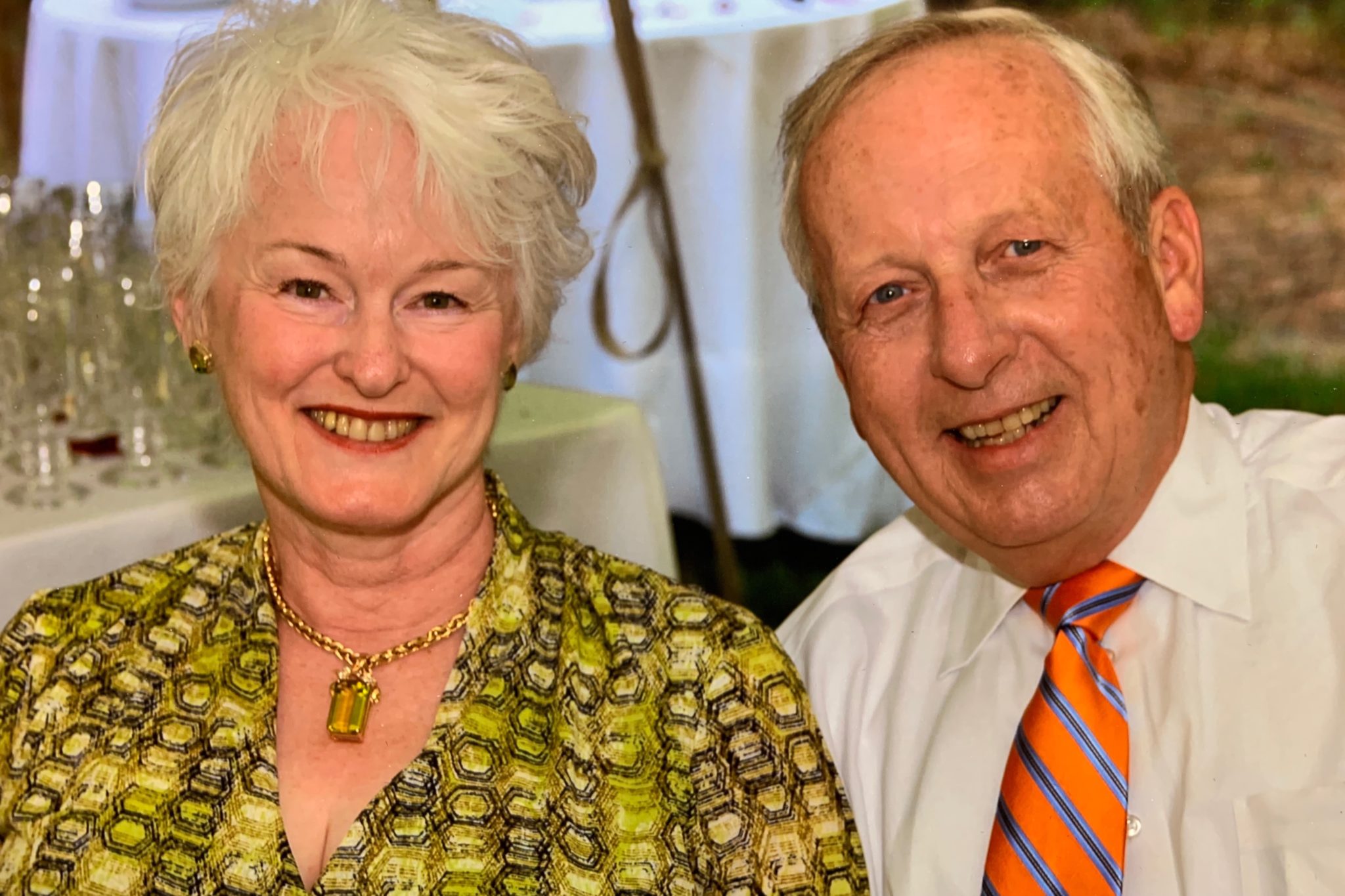 a woman and man sit shoulder to shoulder to pose for a photo