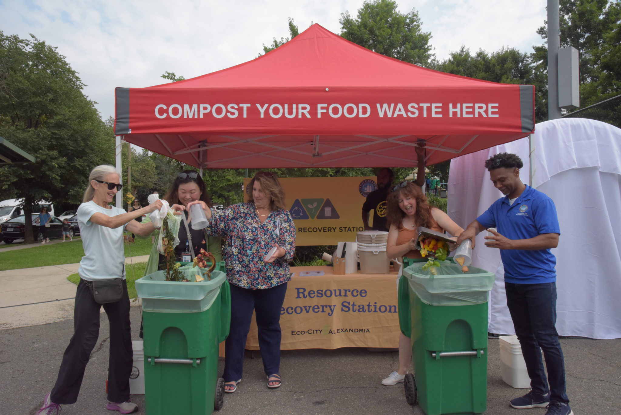 five people dump compost into new compost bins at old town north farmers market