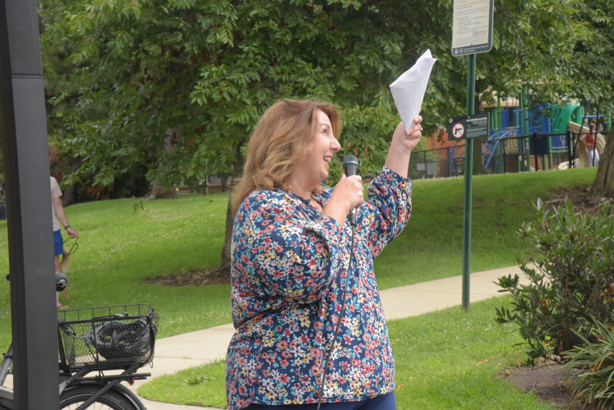 Alexandria Vice Mayor Amy Jackson speaks into a microphone and lifts a piece of paper in the air