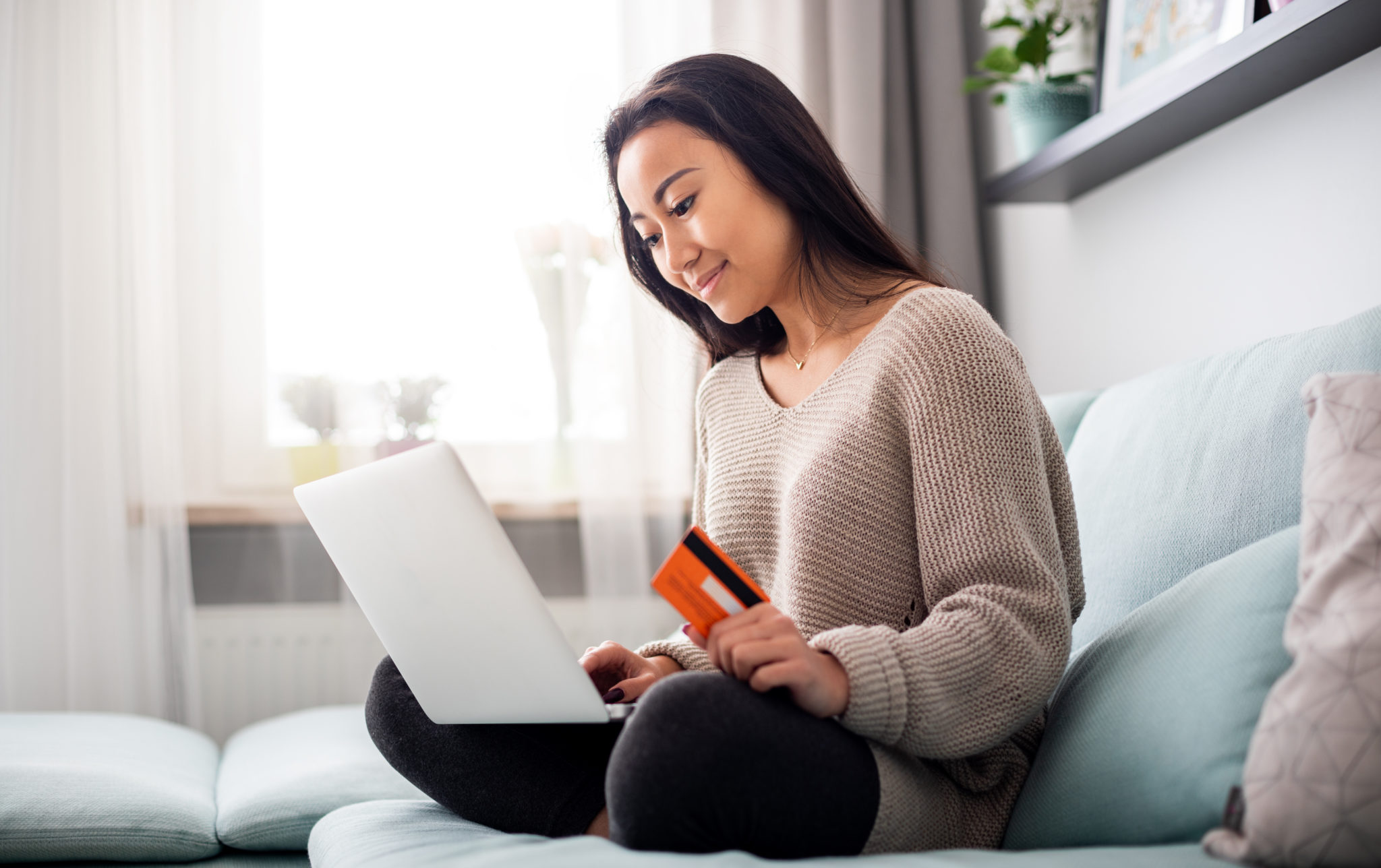 Asian girl making online payment using laptop for shopping at home. (Photo licensed through Adobe Stock)