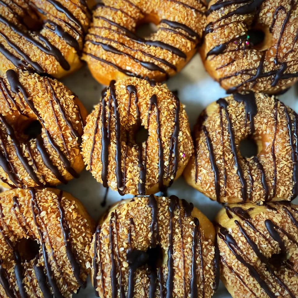 a table of coconut and chocolate doughnuts