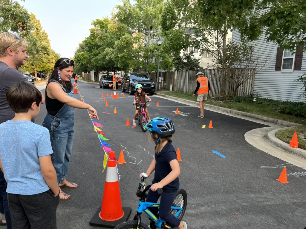 TCP resident Kait Murphy helps her daughter navigate the obstacle course at the Bike Rodeo