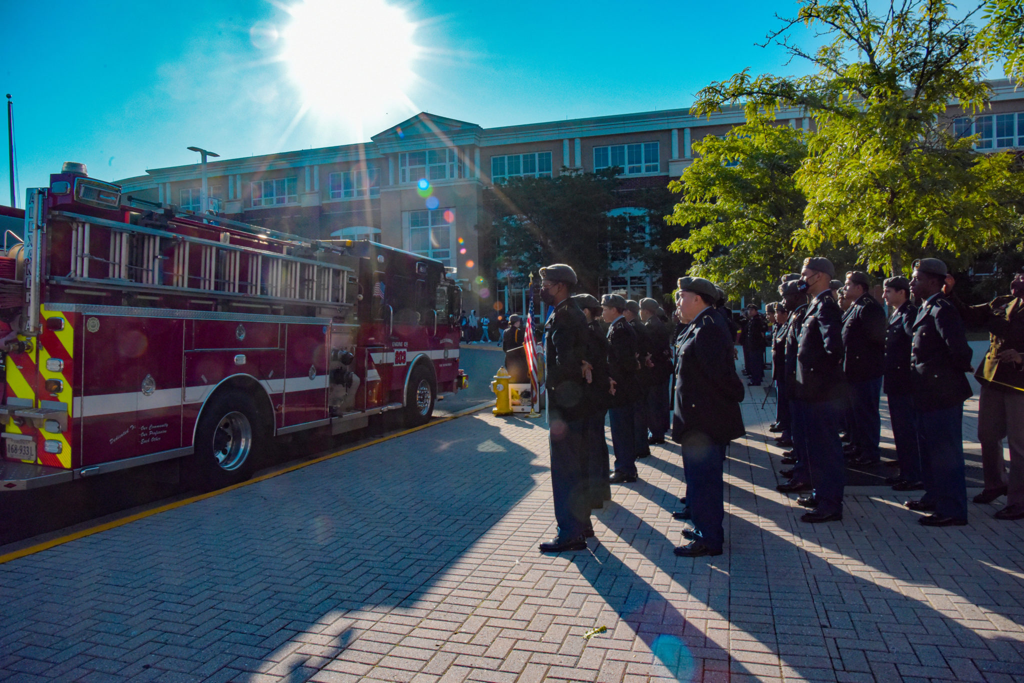 ACHS JROTC outside campus saluting in front of a fire truck for a 9/11 ceremony