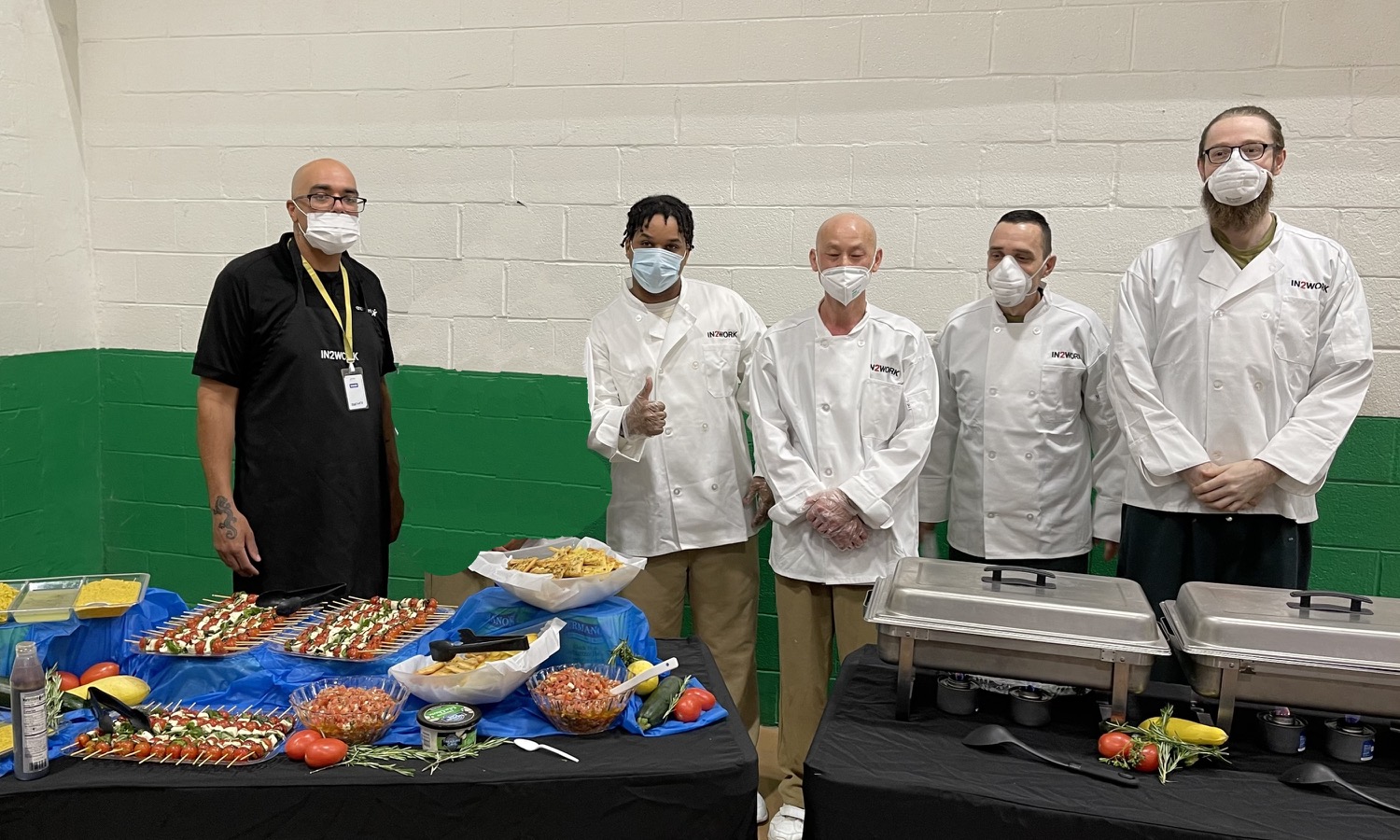 In2Work instructor Brandon Lewis of Aramark, at left, and his students McKinley Moody, Quin Ngoc Rudin, Richard Levin and Mitchell Thompson with the buffet they created for the graduation celebration