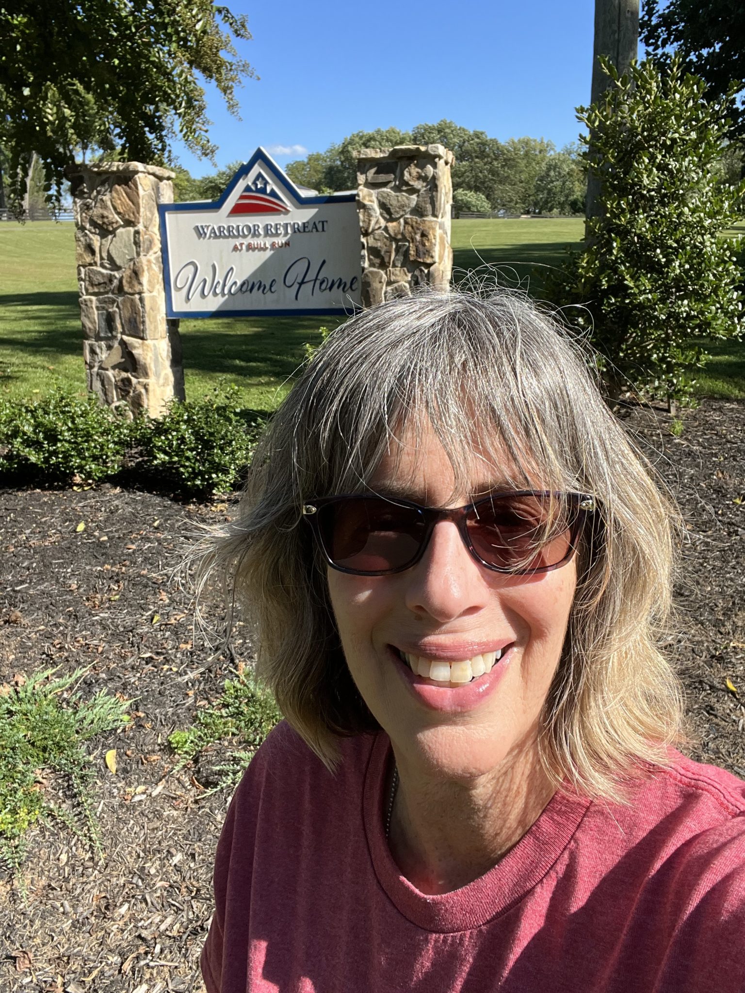 A selfie of woman in front of the Willing Warriors Retreat sign