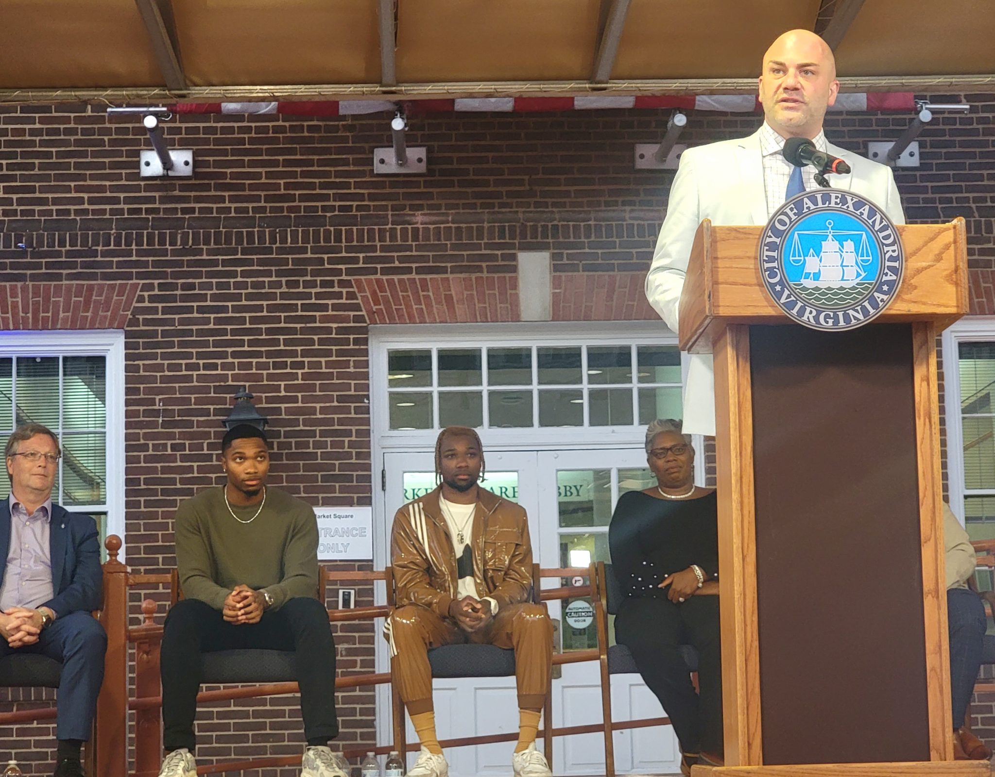 ACHS Principal Peter Balas speaks at podium on a stage outside