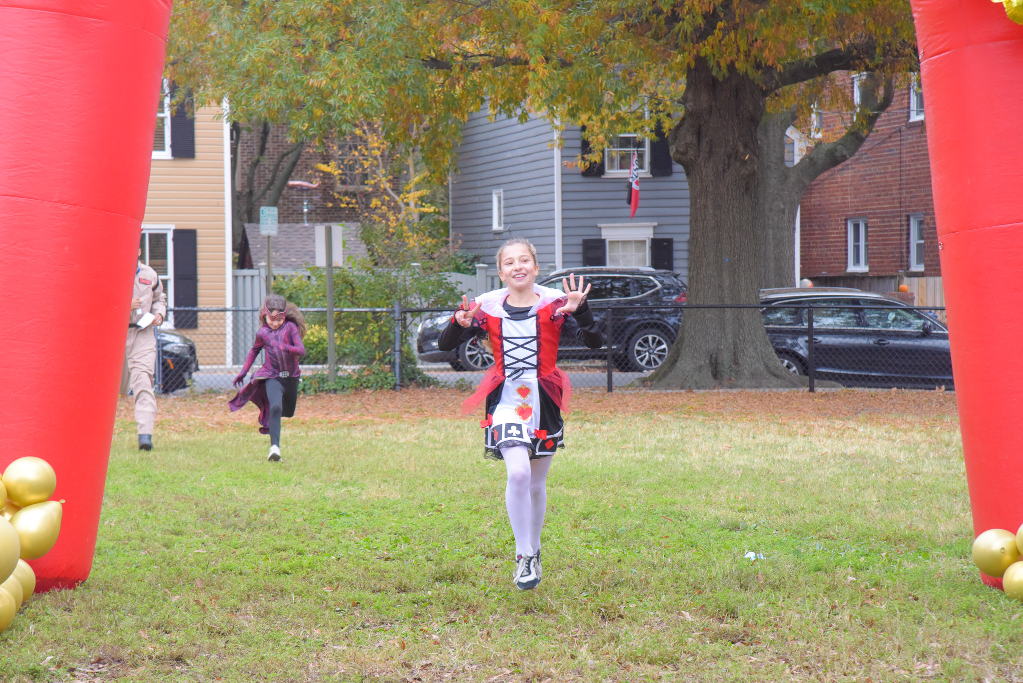 a young girl dressed as the Queen of Hearts runs and holds up seven fingers indicating how many laps she has run