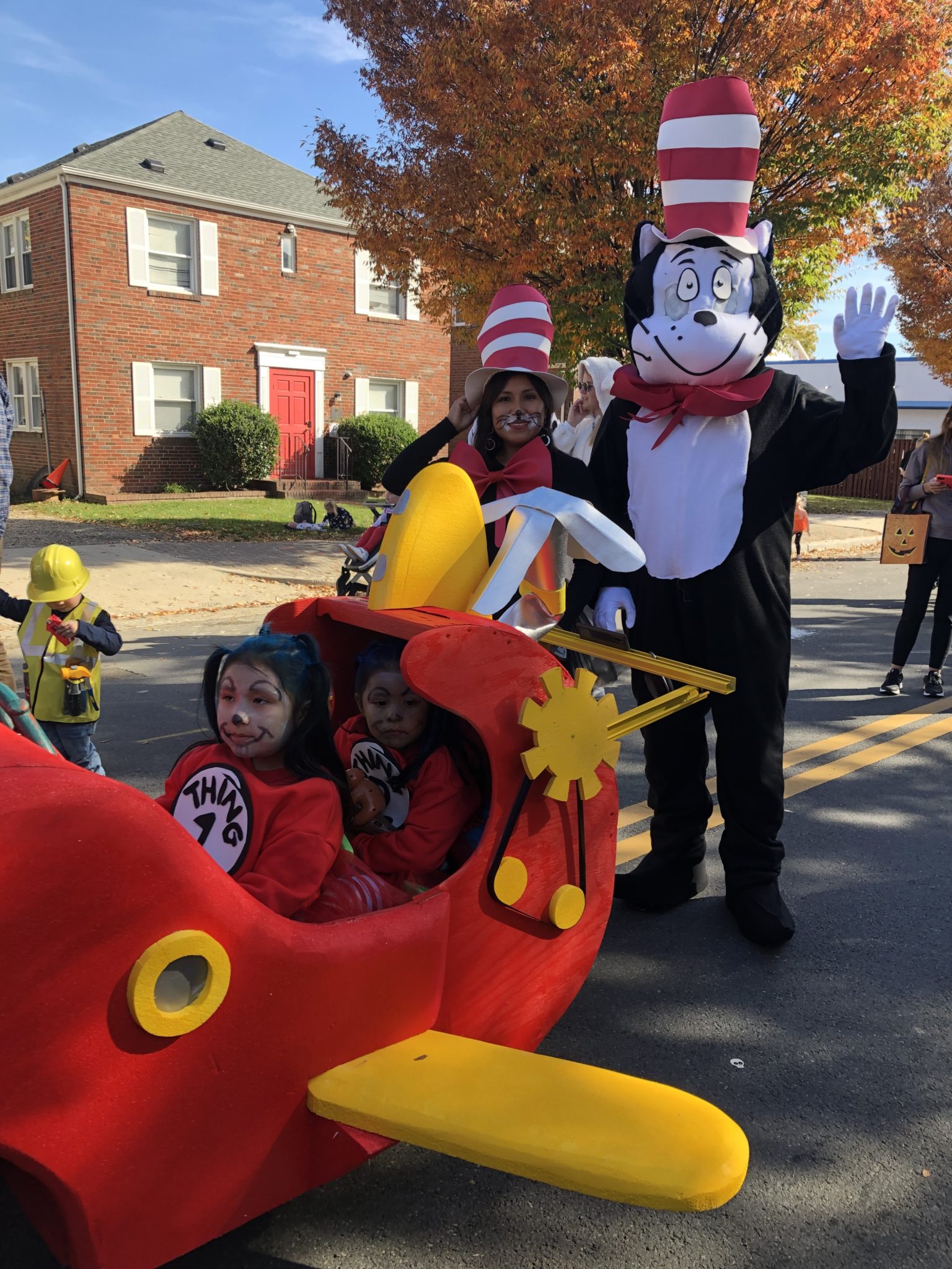 two todderls in a stroller dressed as thing 1 and thing two with parents as the cat in the hat