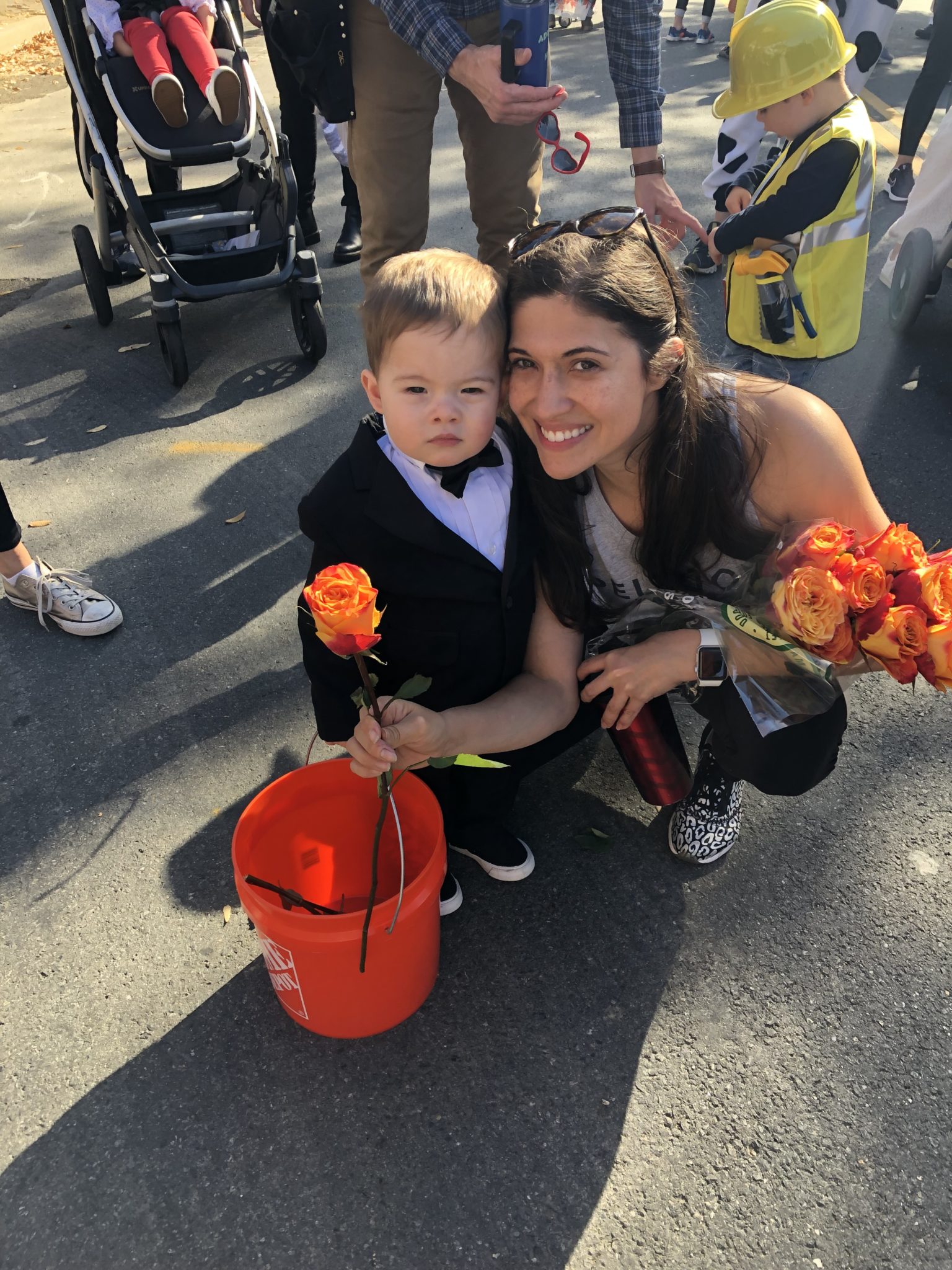 A little boy dressed as The Bachelor handing out roses. 