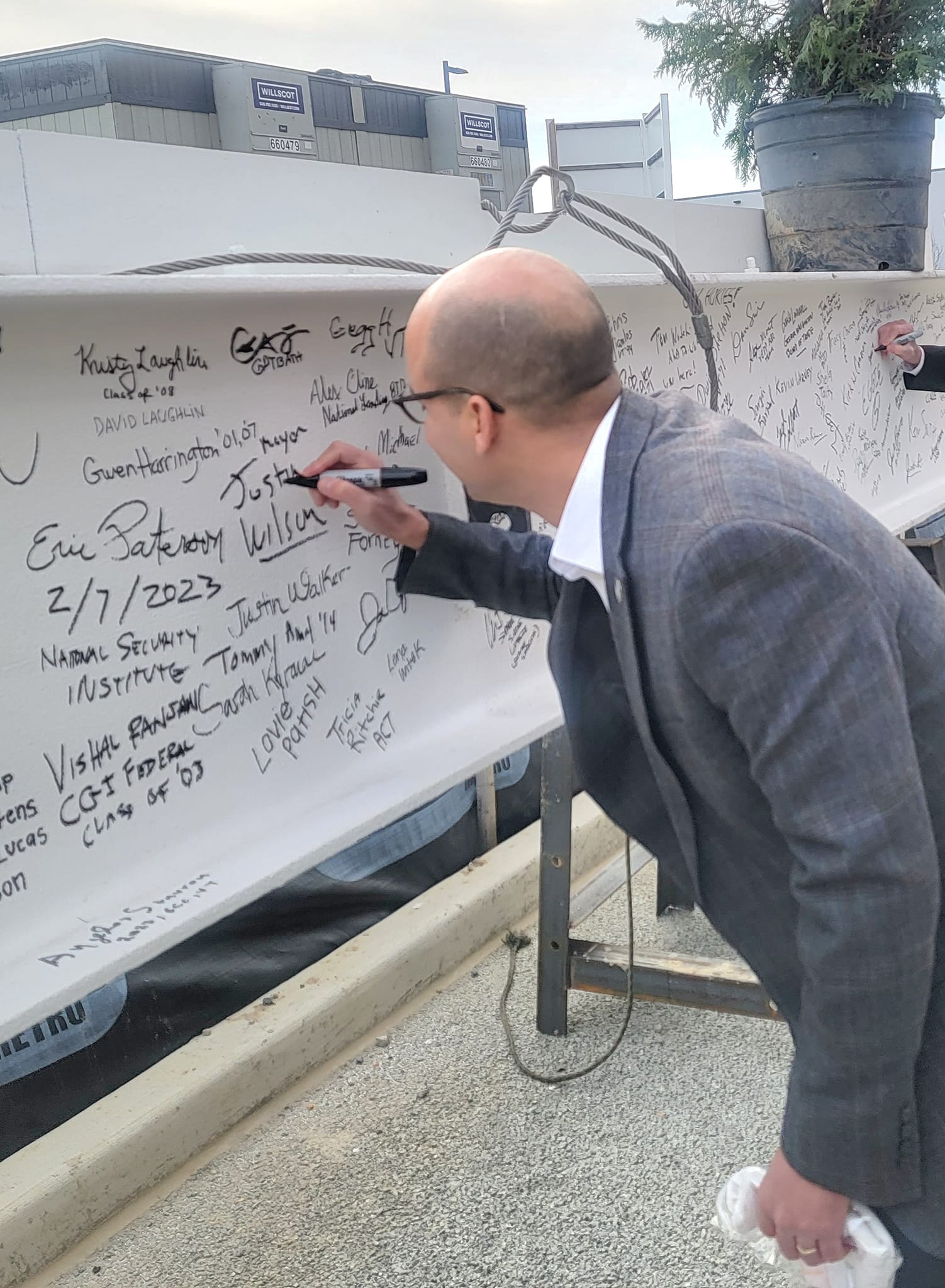 Alexandria Mayor Justin Wilson signs the top beam before it gets raised 11 stories to be put in place atop the first academic building of the Virginia Tech Innovation Campus in Alexandria, Virginia. (Photo: Lucelle O'Flaherty)