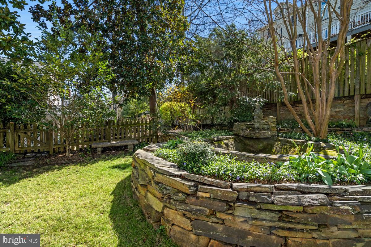 stone walled landscaping and mature trees in manicured lawn