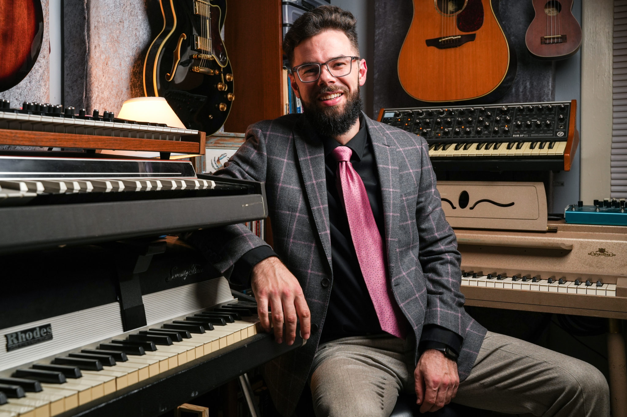 young bearded hipster man with coat and ink tie on at piano