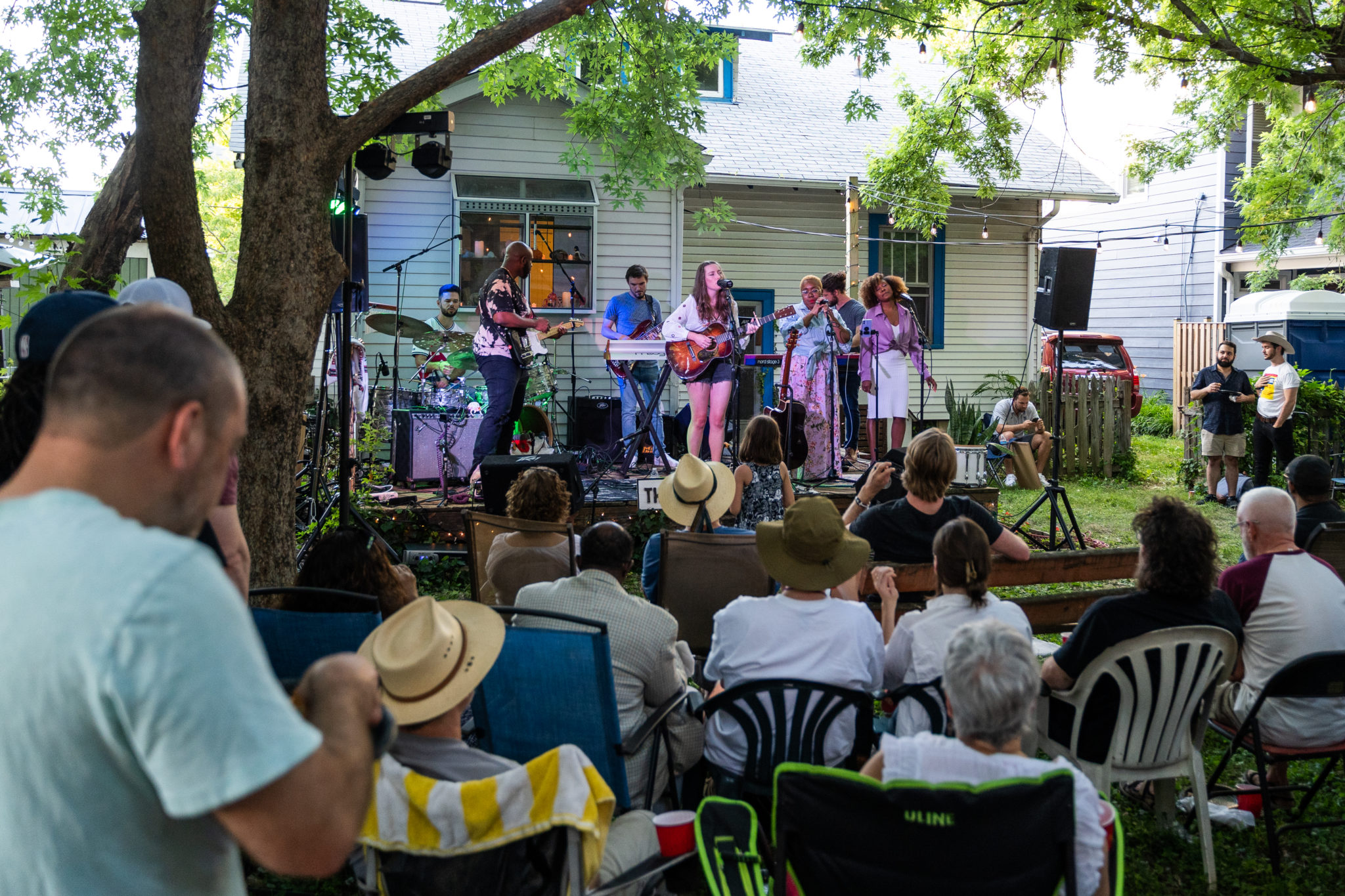 crowd of people and back yard stage with musicians playing