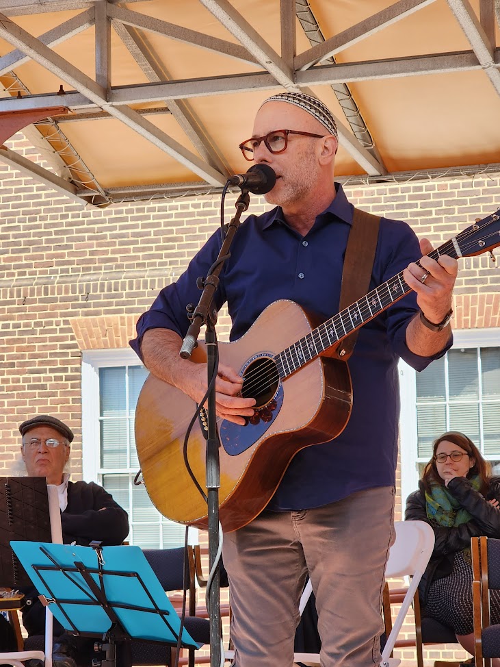 Man at microphone playing guitar and singing.