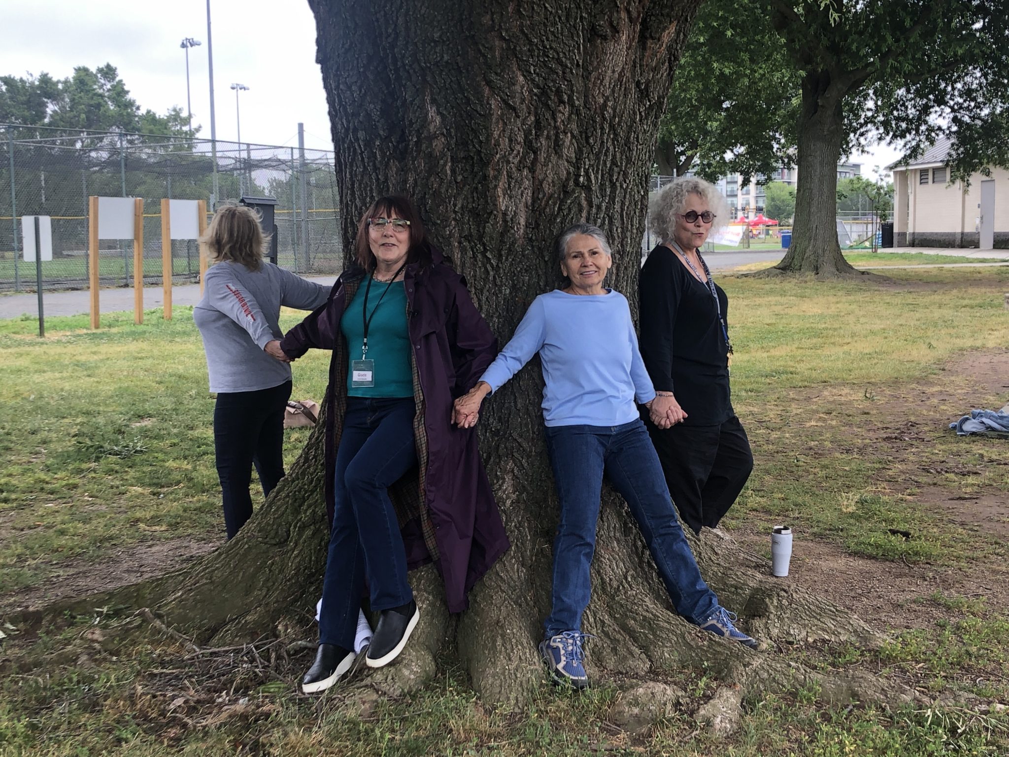 Gisele McAuliffe (2nd from left) and other residents joining hands around a Willow Oak tree. (Photo: Peerawut Ruangsawasdi/The Zebra Press)