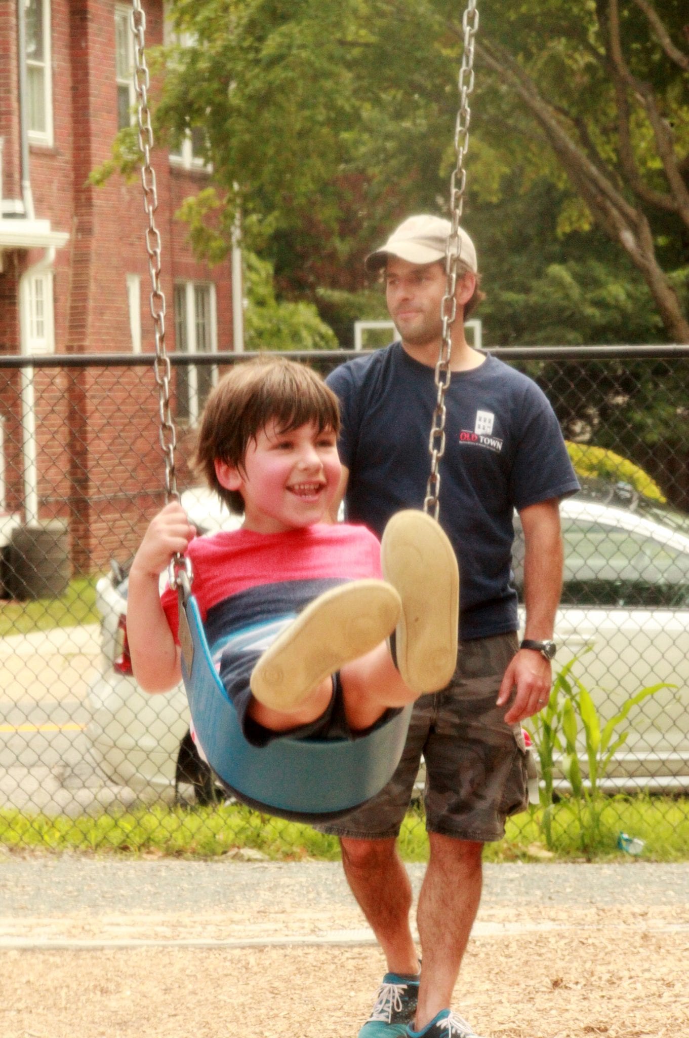 Little boy on swing with dad pushing him