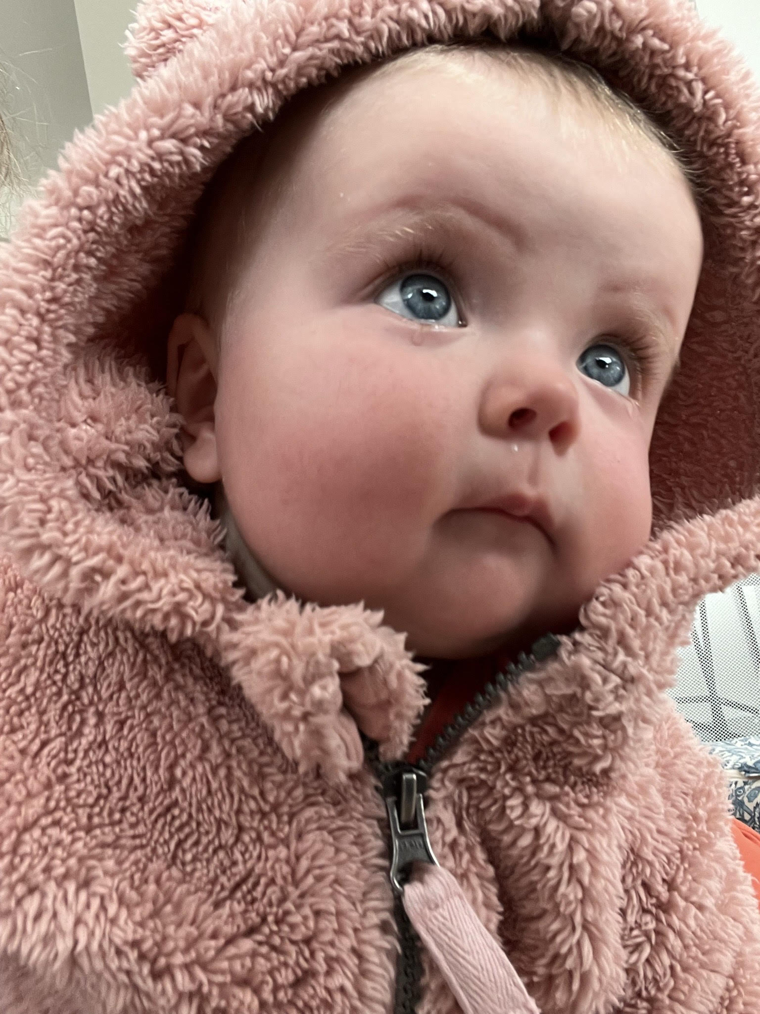 Baby with blue eyes and small tears forming looking upward