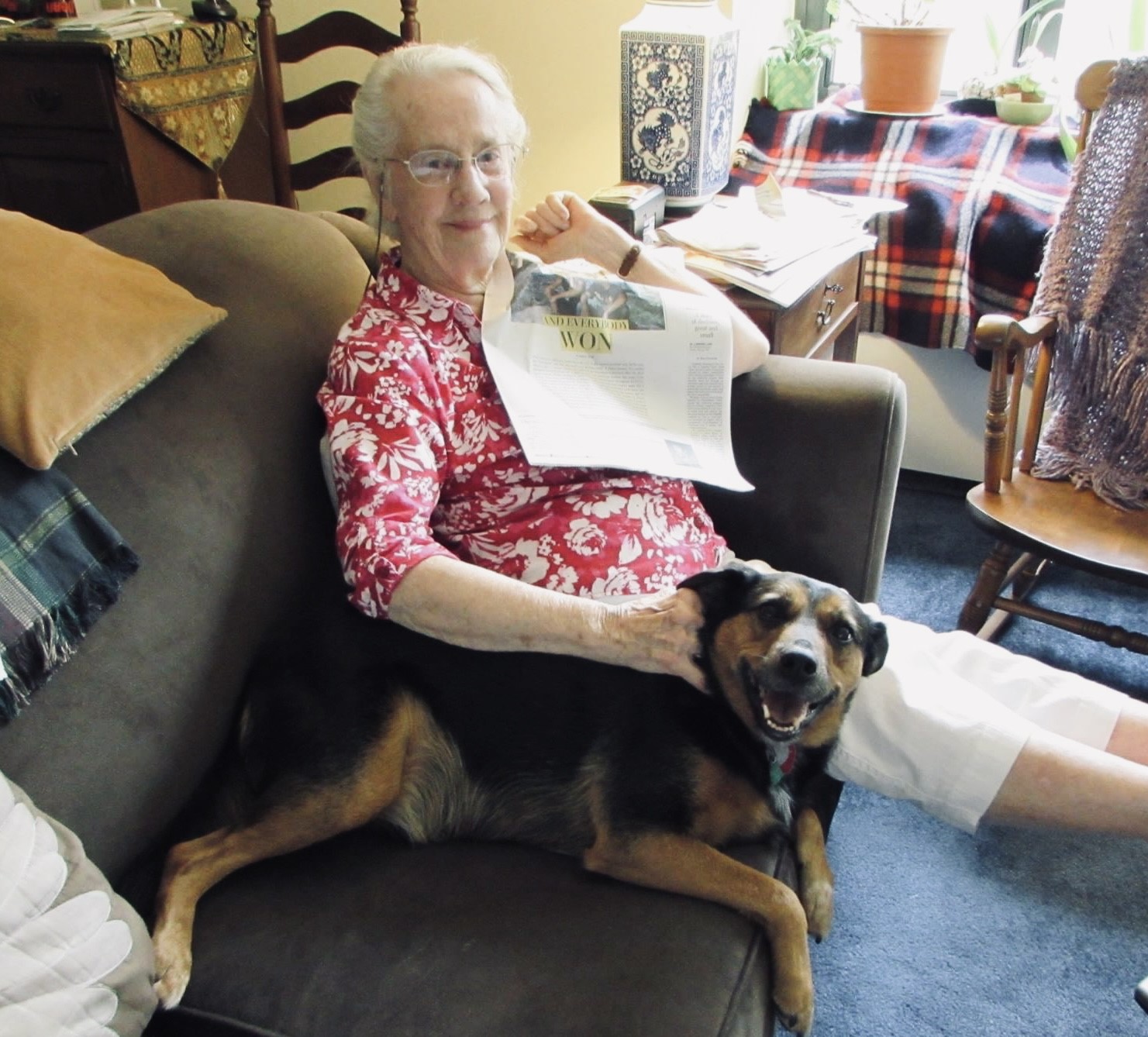 Elderly lady on sofa with black and brown dog.